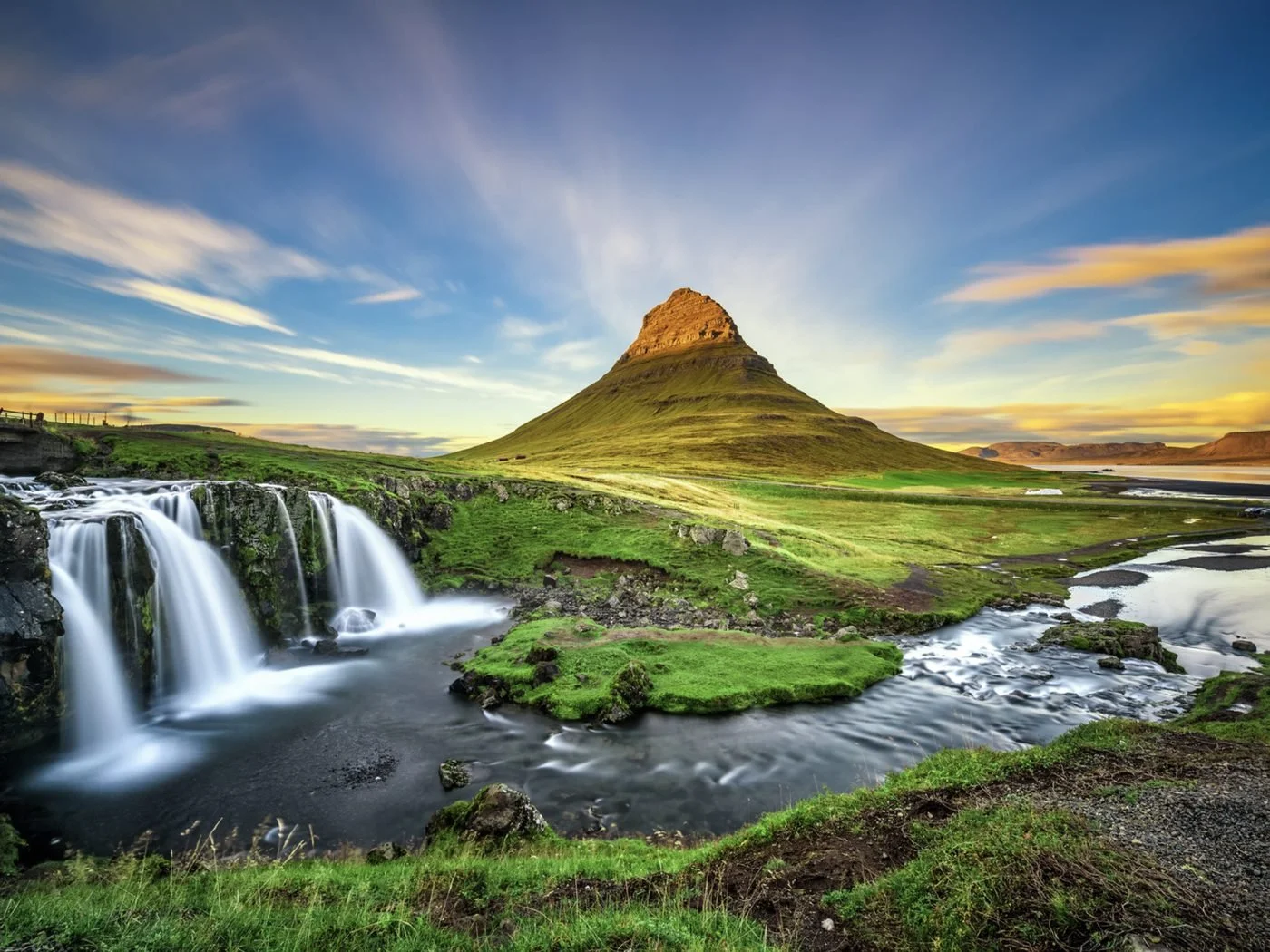 Kirkjufellsfoss waterfall and Kirkjufell mountain in Iceland in golden evening light
