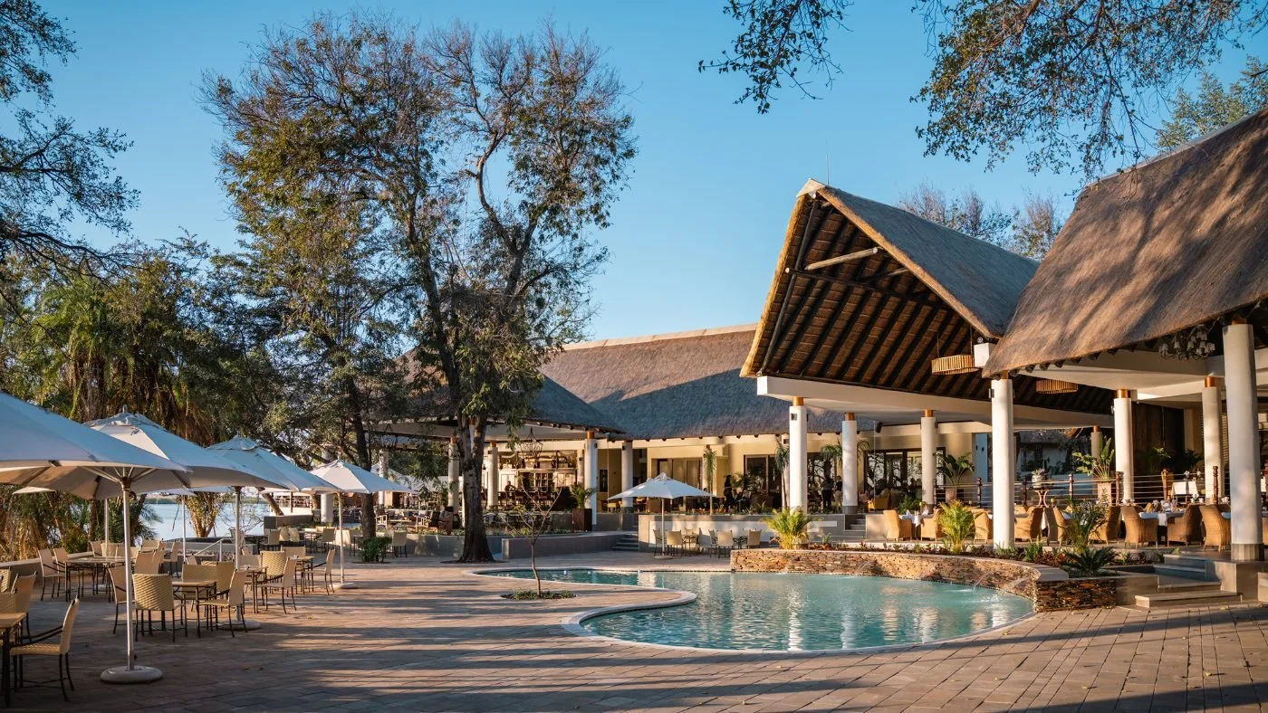 The pool at Chobe Safari Lodge, with thatched buildings and umbrellas