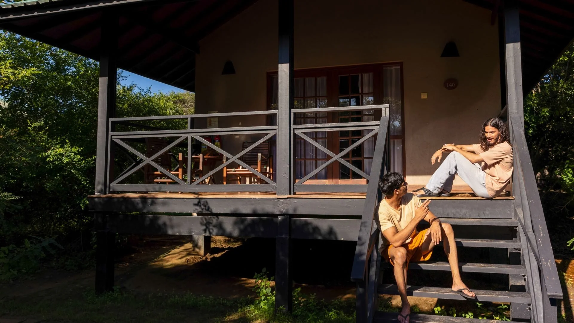 Two guests relaxing on the steps of a Jungle Chalet at Cinnamon Wild Yala