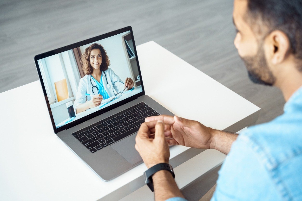Online medical consultation, view of a man using a laptop, doctor on screen.