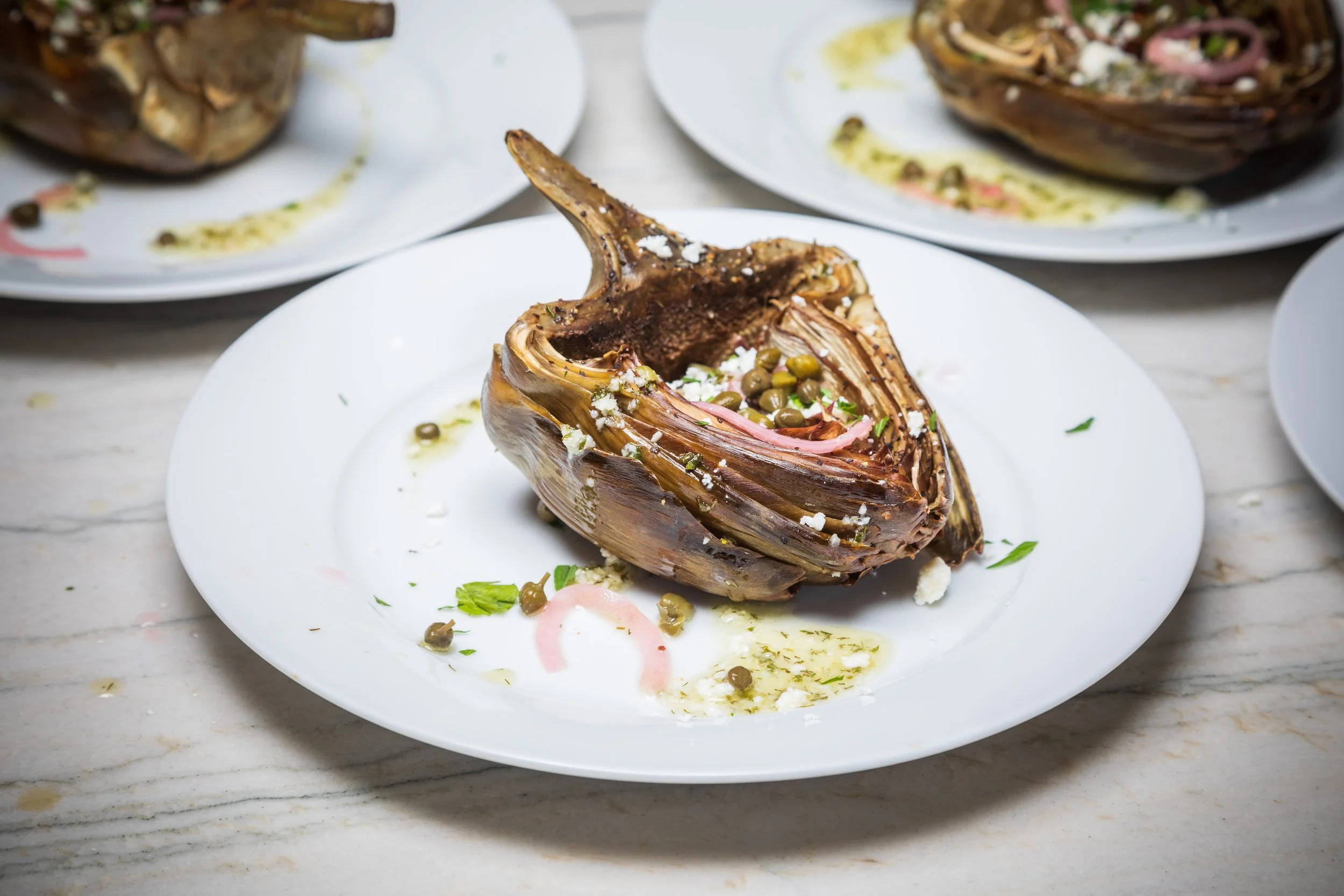 Grilled artichoke with capers, feta, and herbs – elegant plant-forward starter for birthdays and small group dinners