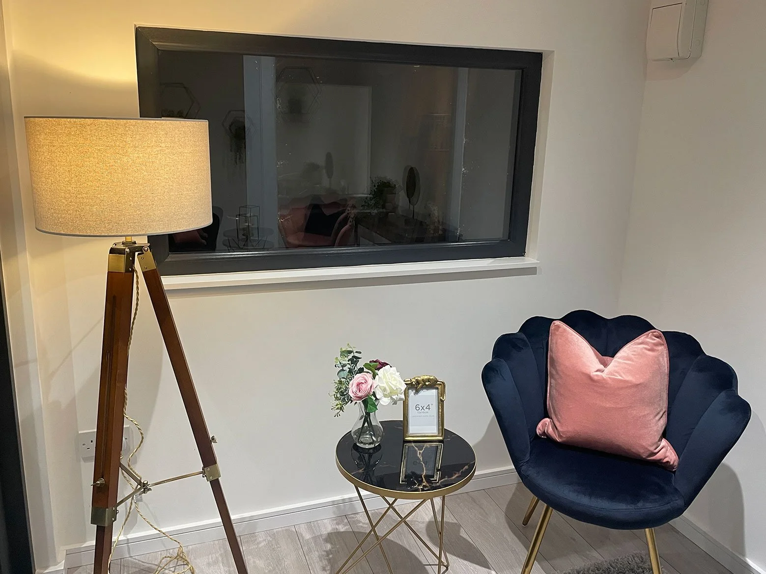  A compact room adorned with a chair, lamp, and a window, offering a tranquil atmosphere. 