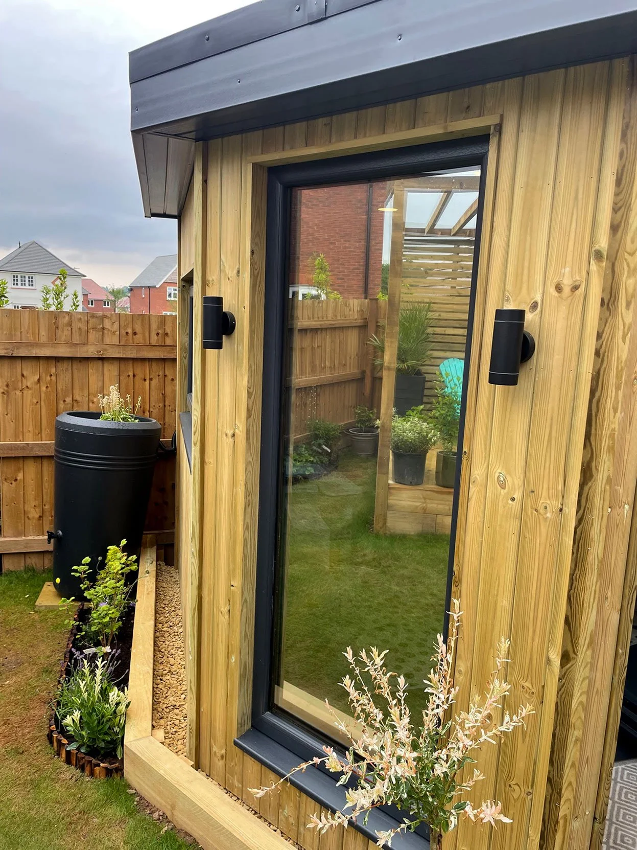  Charming garden room featuring a wooden door and window, providing a tranquil space amidst nature. 
