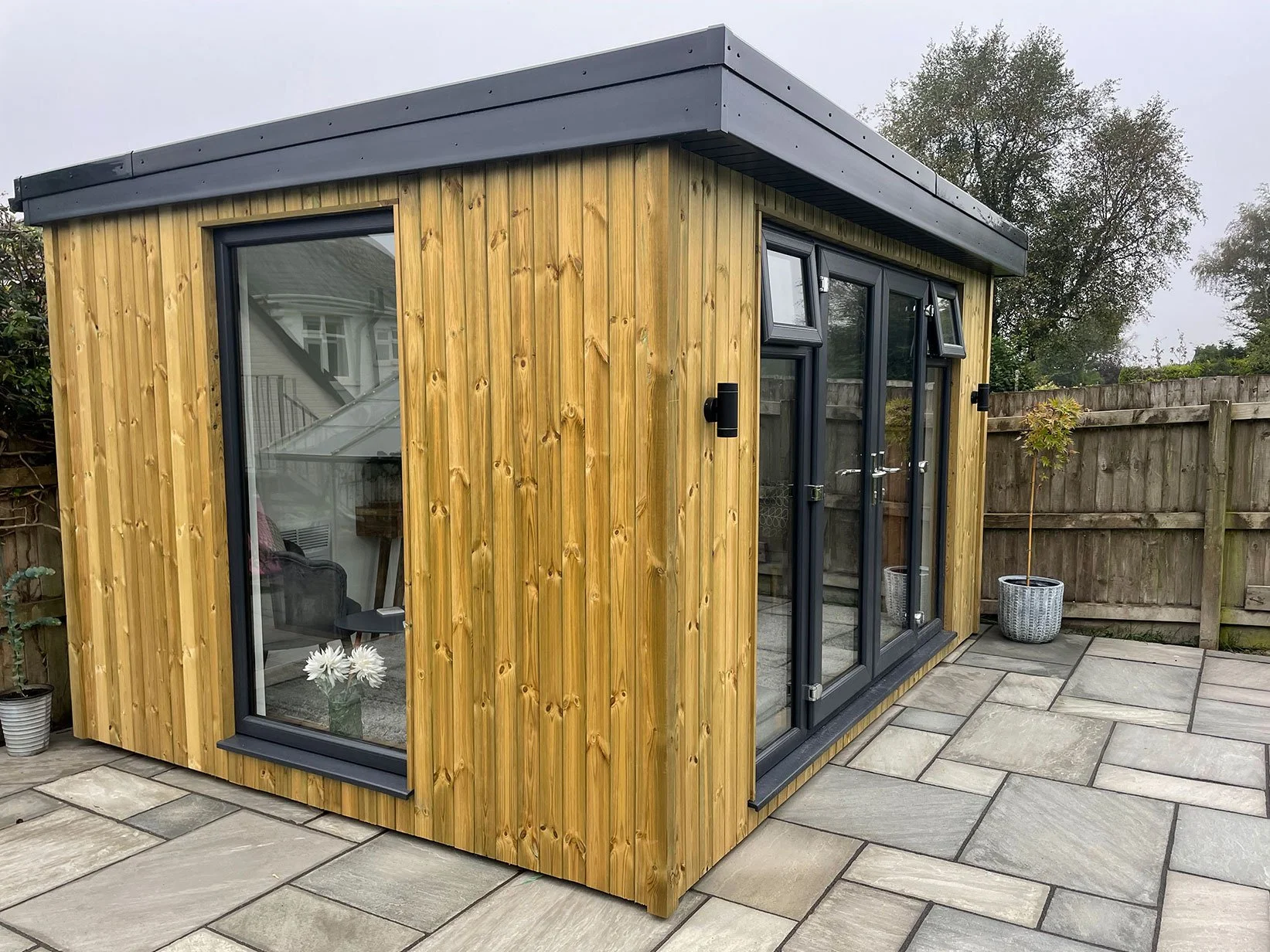  Elegant garden office with a wooden roof and sliding doors, blending seamlessly with the natural surroundings. 