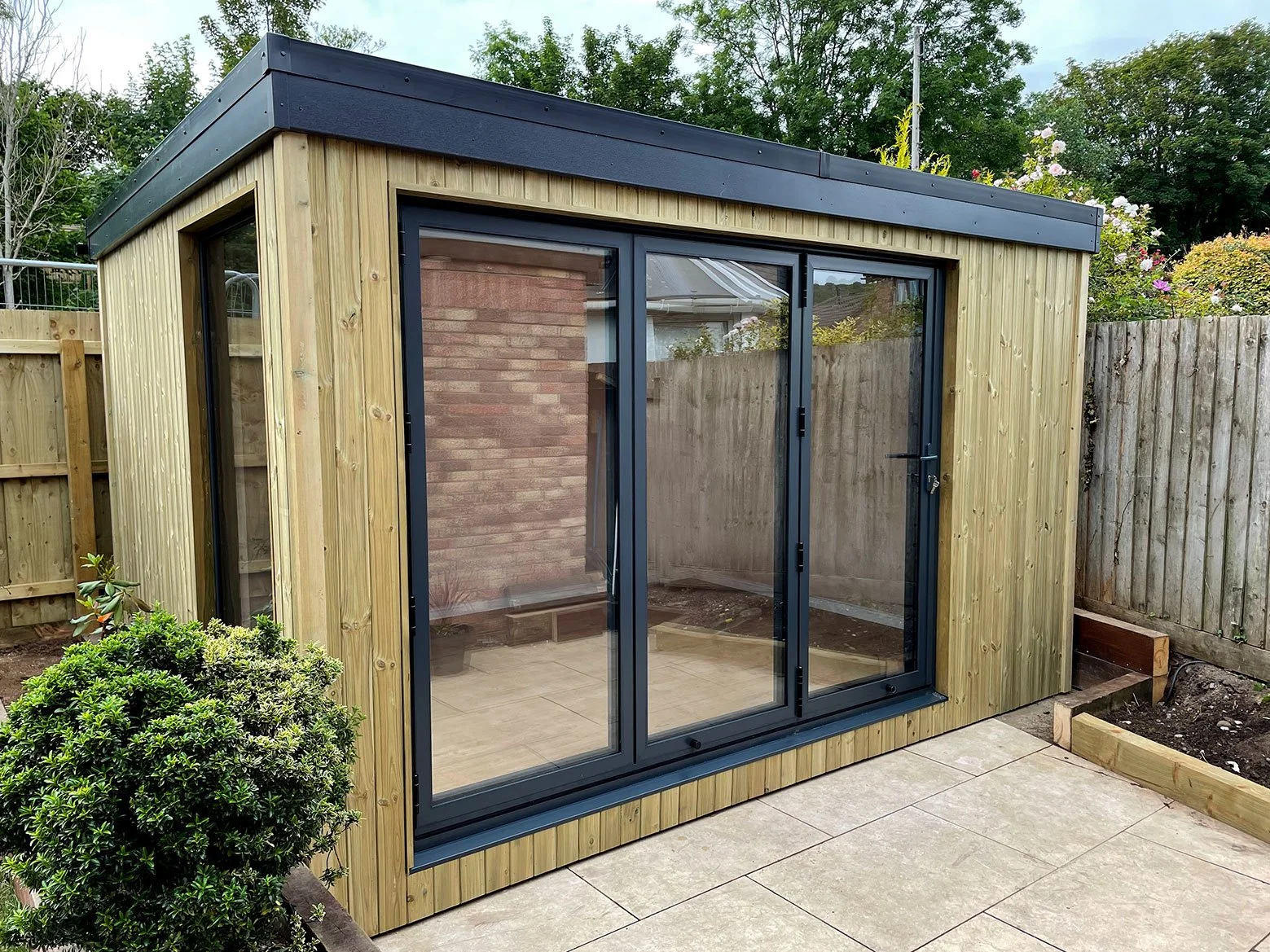  Garden room with sliding doors and wooden deck, providing a serene outdoor space. 