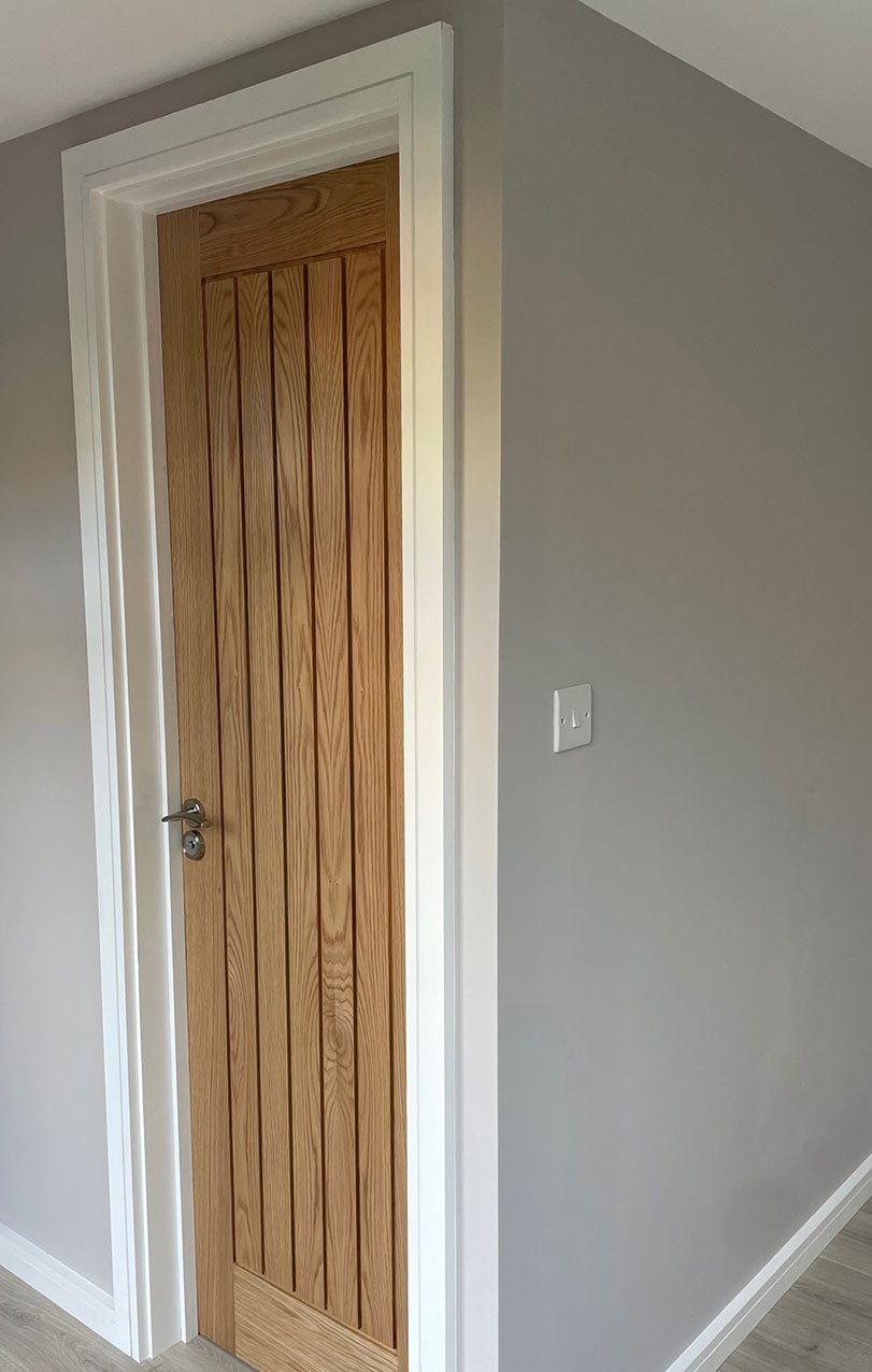  A simple room featuring a wooden door and a pristine white wall. 