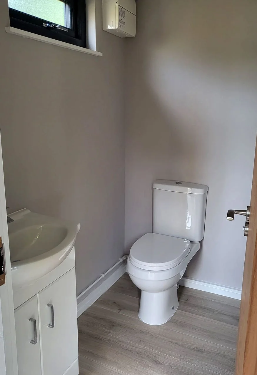  A well-lit bathroom featuring a toilet, sink, and a window providing natural light and ventilation. 