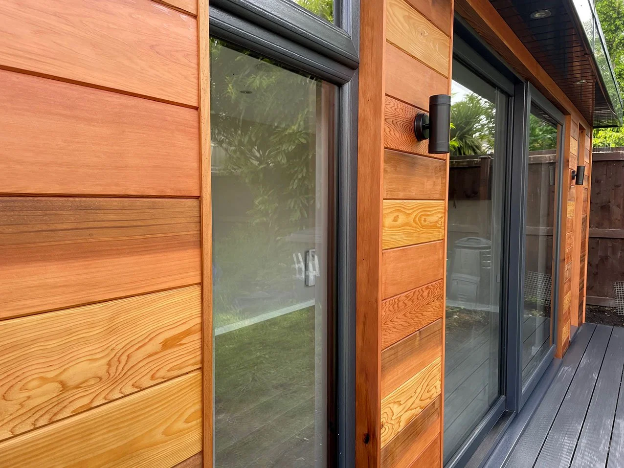  An outdoor space featuring a wooden deck, sliding glass doors, and a wooden fence, enhanced by a living roof. 