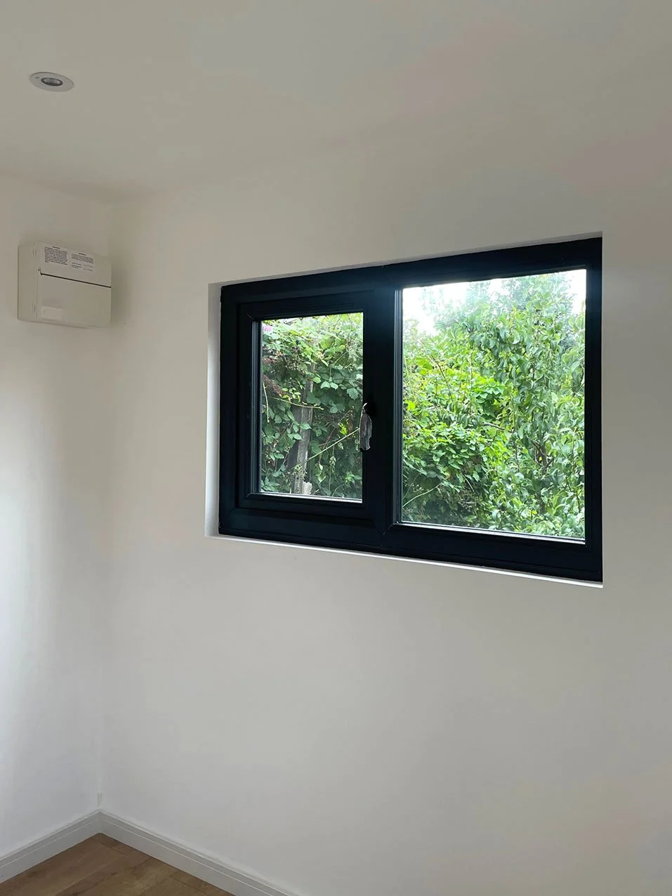  A minimalist room with a window and a white wall, creating a serene and bright atmosphere. 