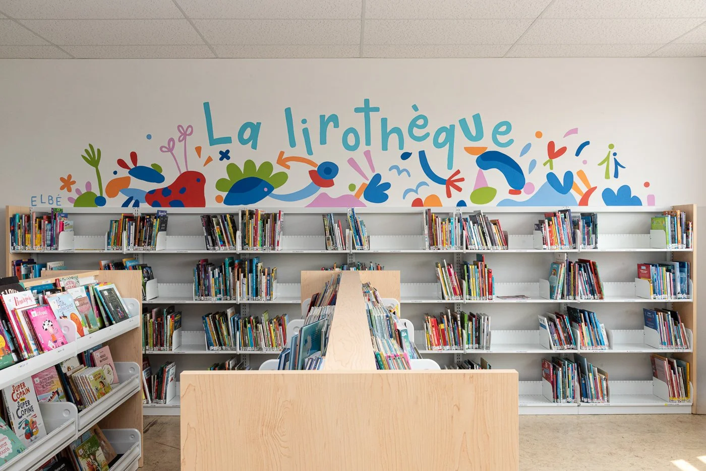 Murale abstraite colorée d’Elbé peinte au-dessus des rayonnages d’une bibliothèque