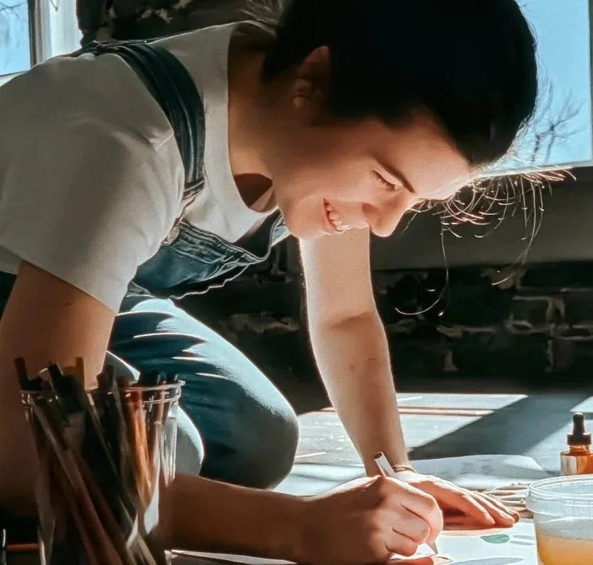 Artist Elbé painting a colorful artwork in her sunlit studio