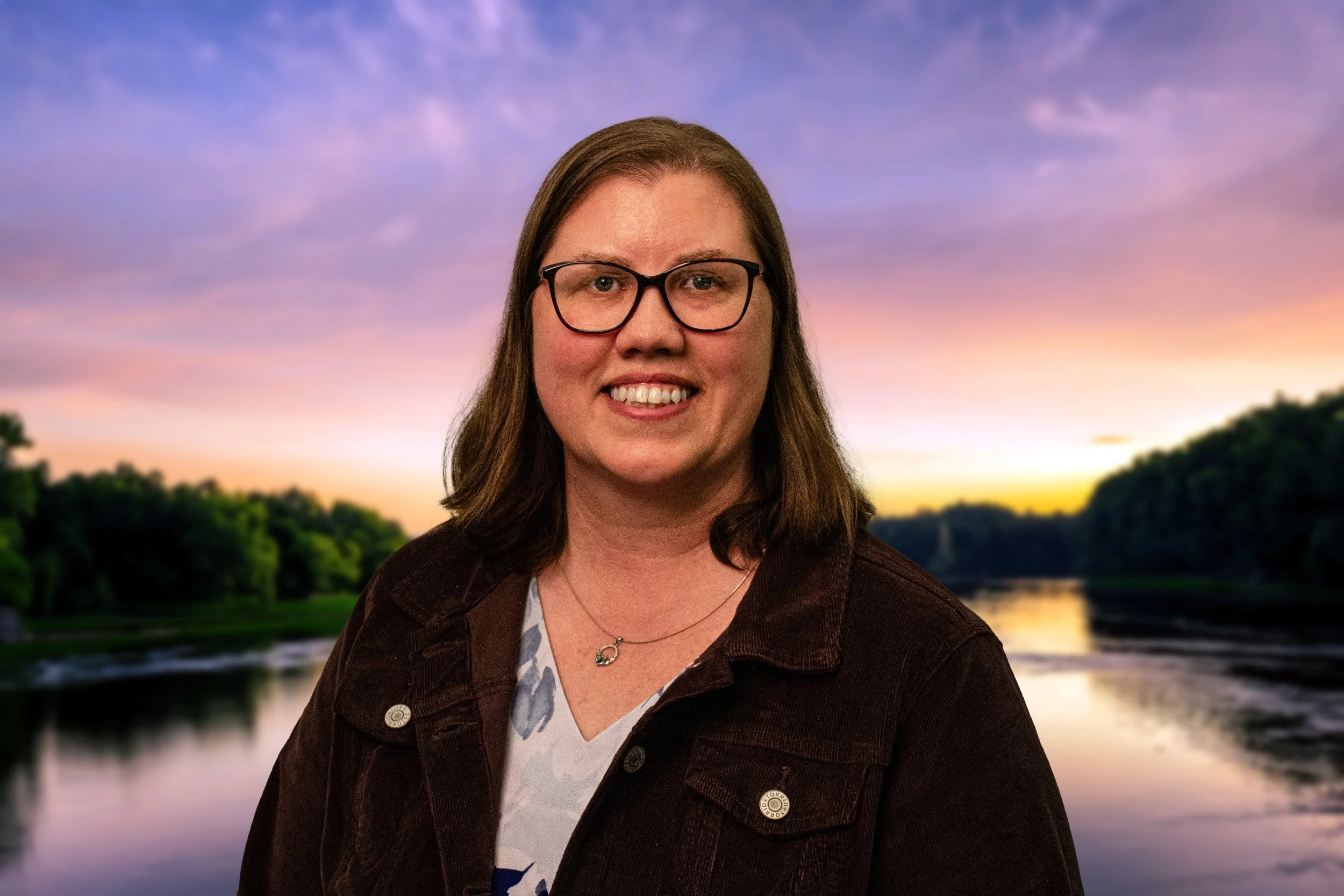 Pastor Sarah smiling in a headshot with a river sunset in the background