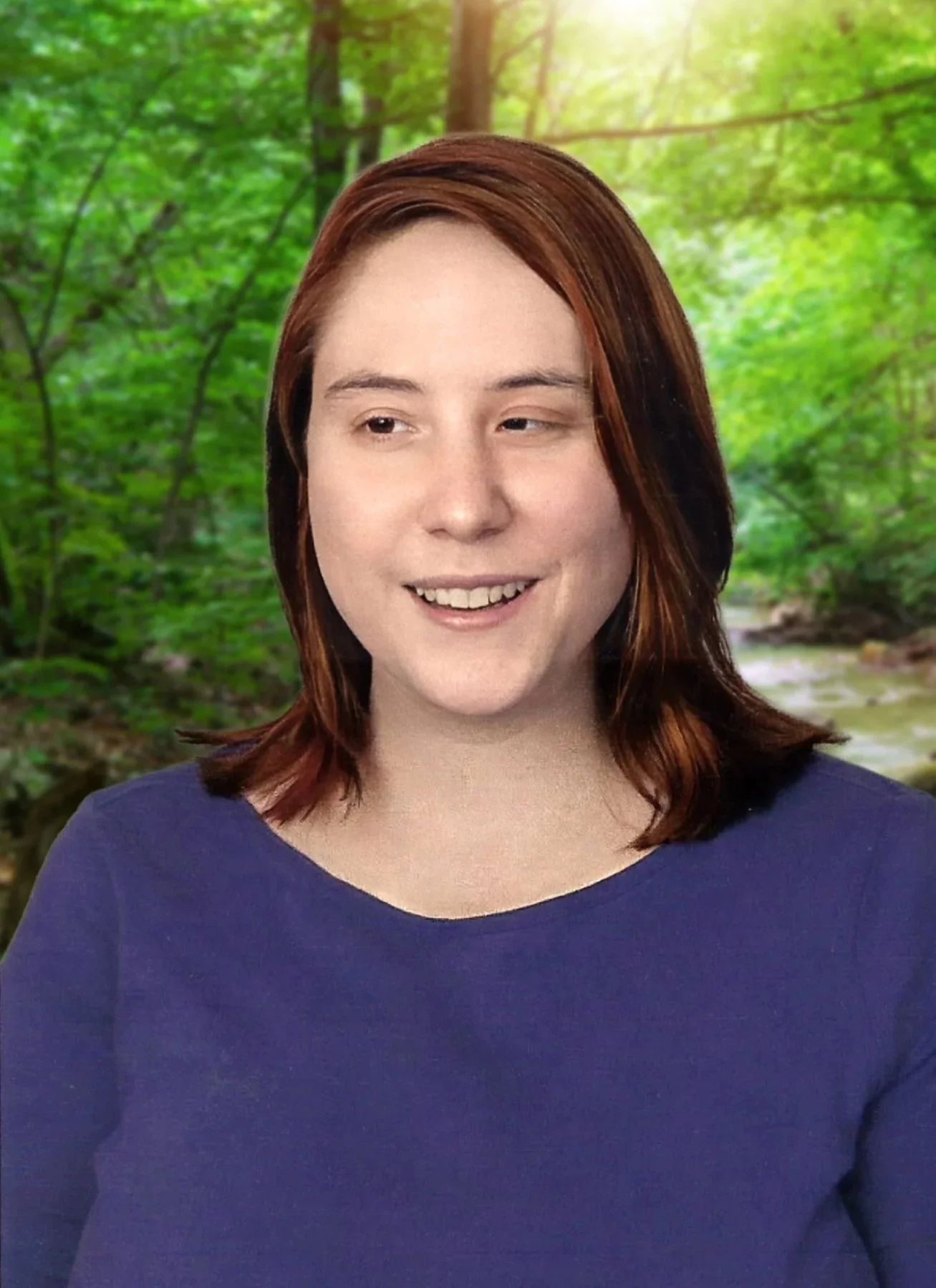 Rev. Laura Fanizza smiles while standing in front of a lush green forest with sunlight filtering through the trees. She has shoulder-length brown hair and wears a dark blue top.