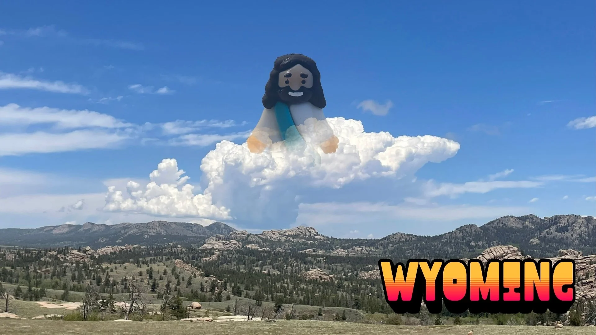 Tiny Jesus figurine emerging from clouds above a Wyoming mountain landscape under a bright blue sky. Text reads WYOMING.