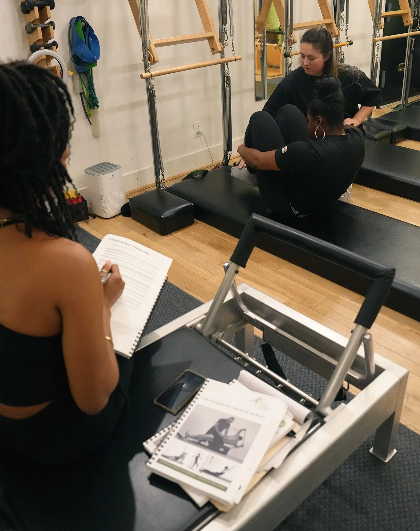 Pilates instructor class with three students learning in a studio.
