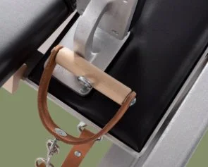 Close-up of a horse stirrup hanging from a saddle on a black saddle stand, with a green background.