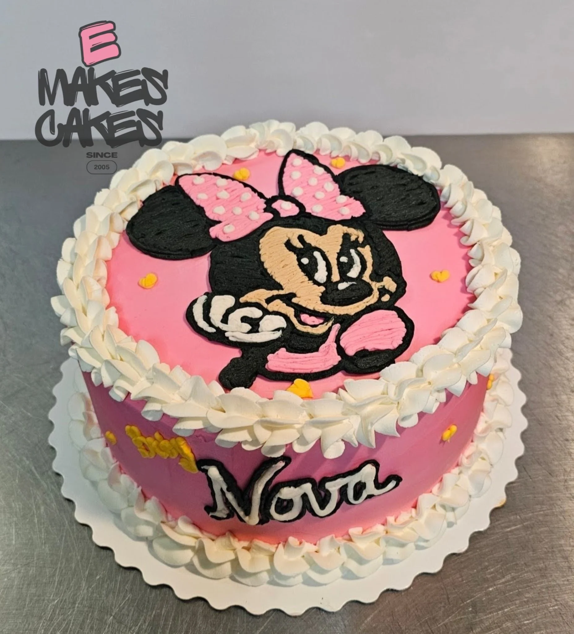 Cake featuring Minnie Mouse with a pink bow, a pink background, white border, and the name 'Nova' written on it. E Makes Cakes