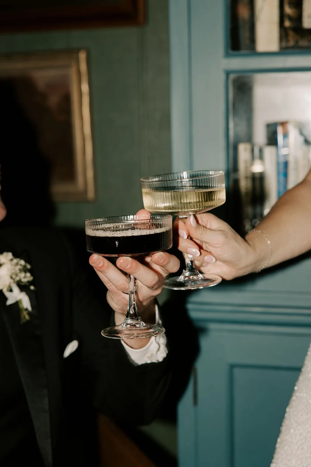 Wedding couple holding champagne coupe flutes during a photoshoot in the library at The Westport in Chico, California