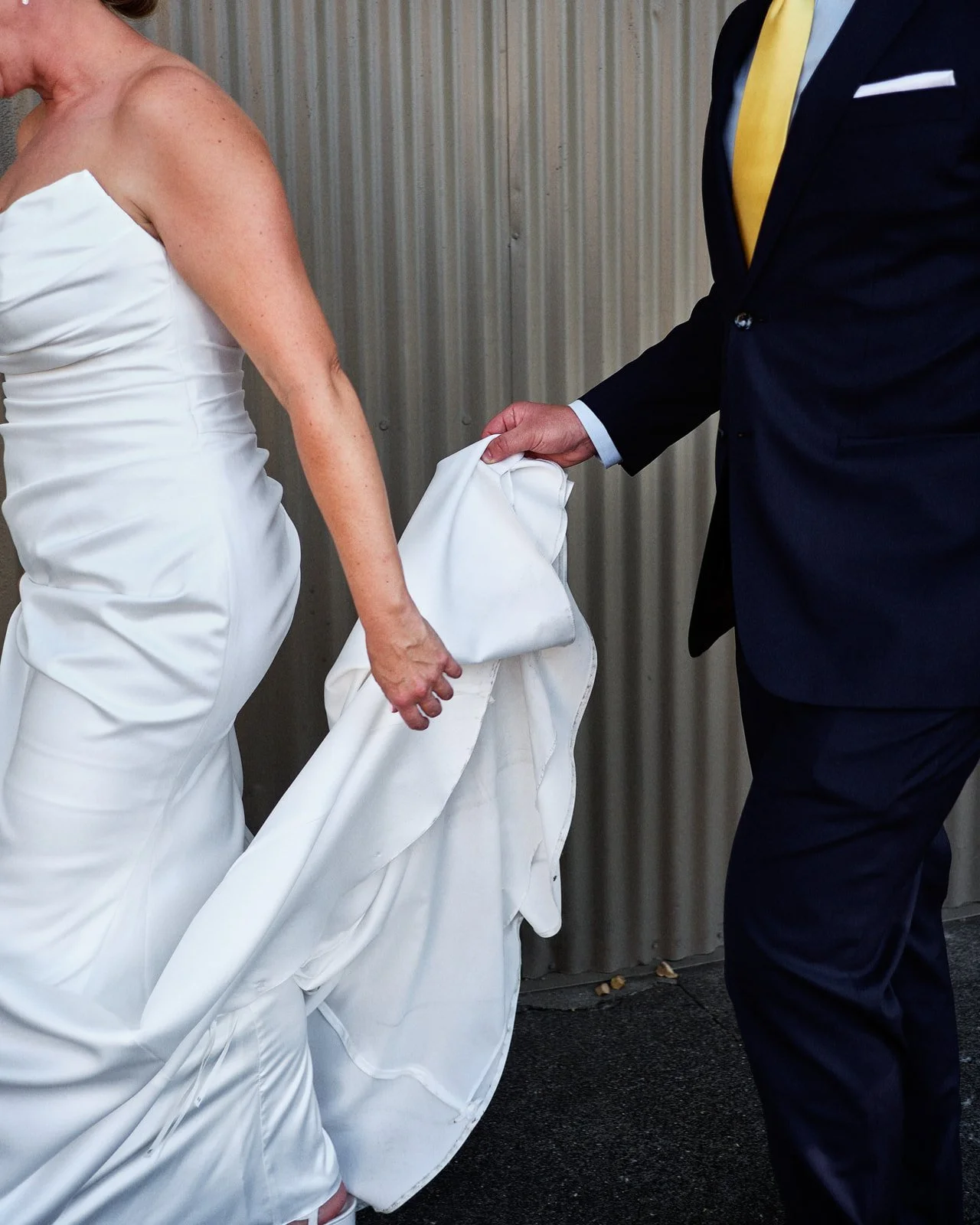 Groom holds bride's gown outside the Westport in downtown Chico