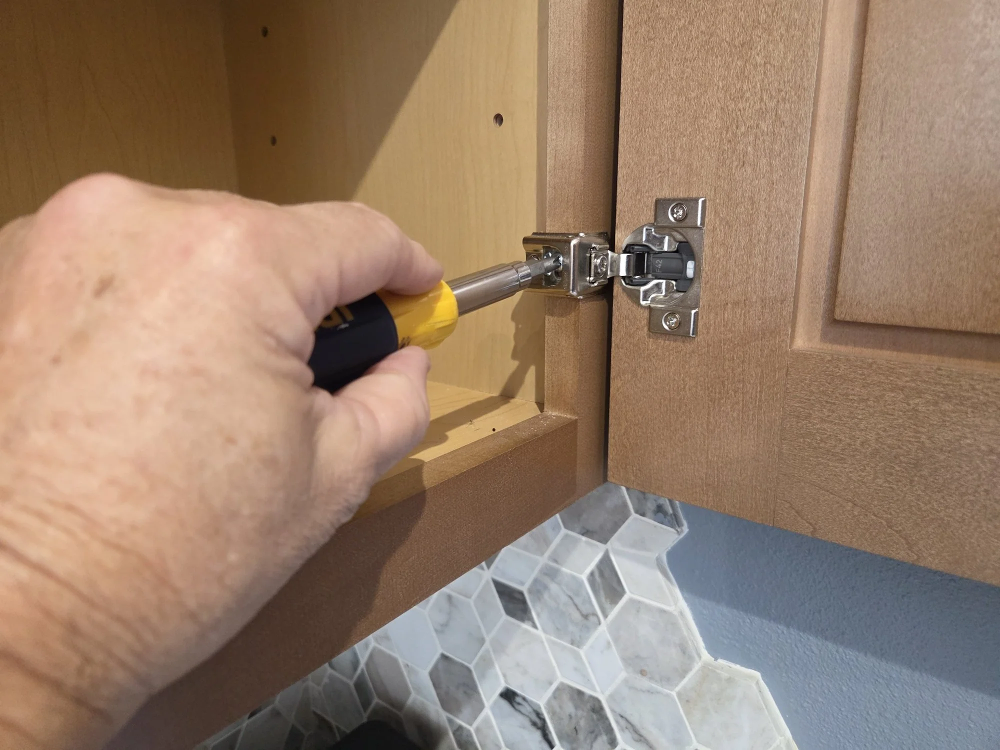 handyman adjusting kitchen cabinet door hinge