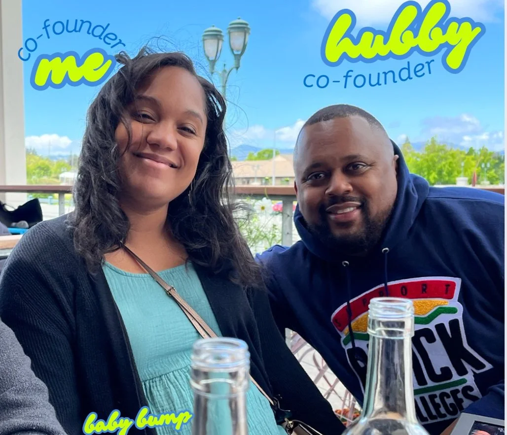 Smiling man and woman seated outdoors with text 'co-founder me,' 'hubby co-founder,' and 'baby bump' overlayed. The woman looks pregnant, wearing a blue top, and the man wears a dark hoodie. Bottles are on the table.
