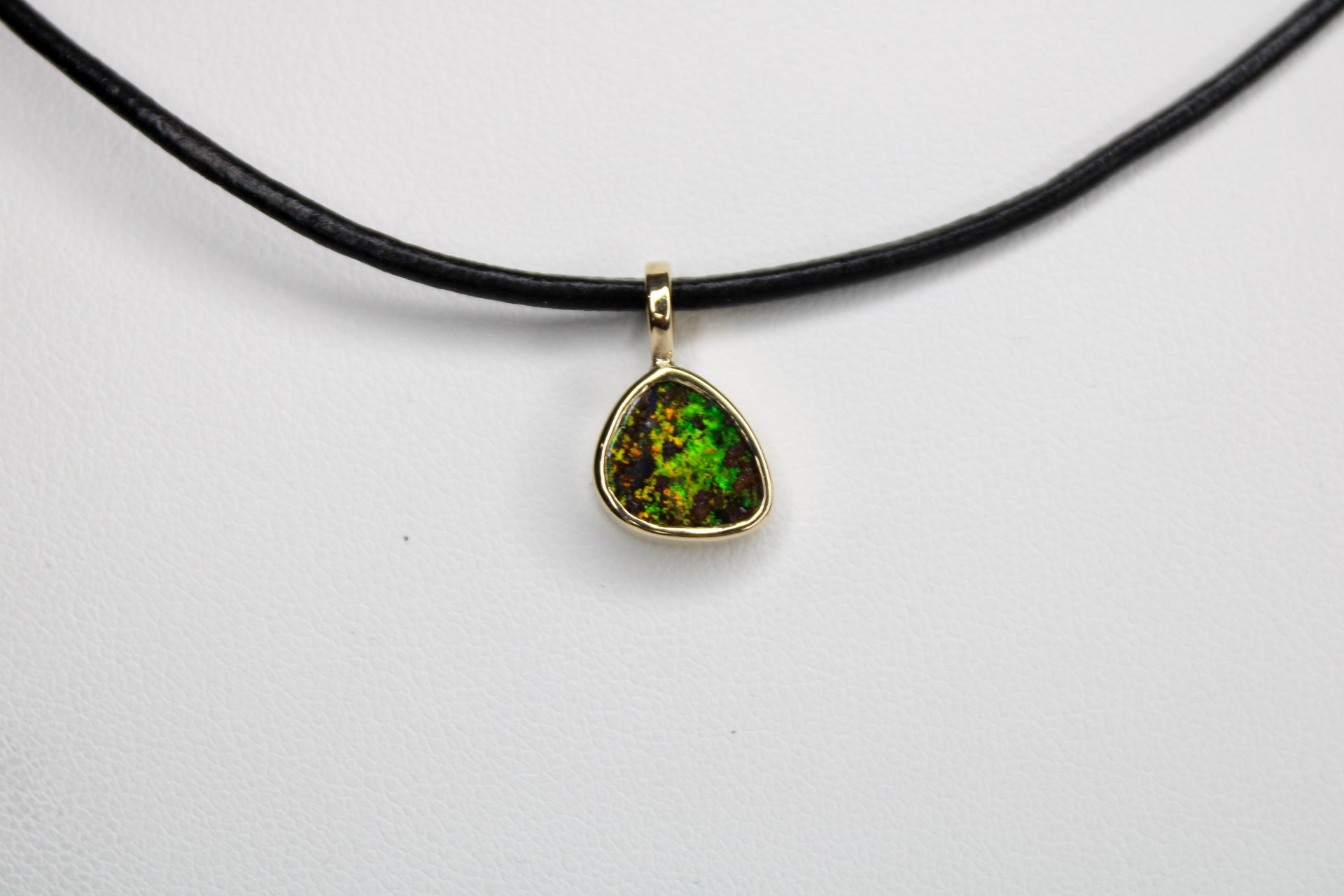 Pendant necklace with a green and brown gemstone on a black cord