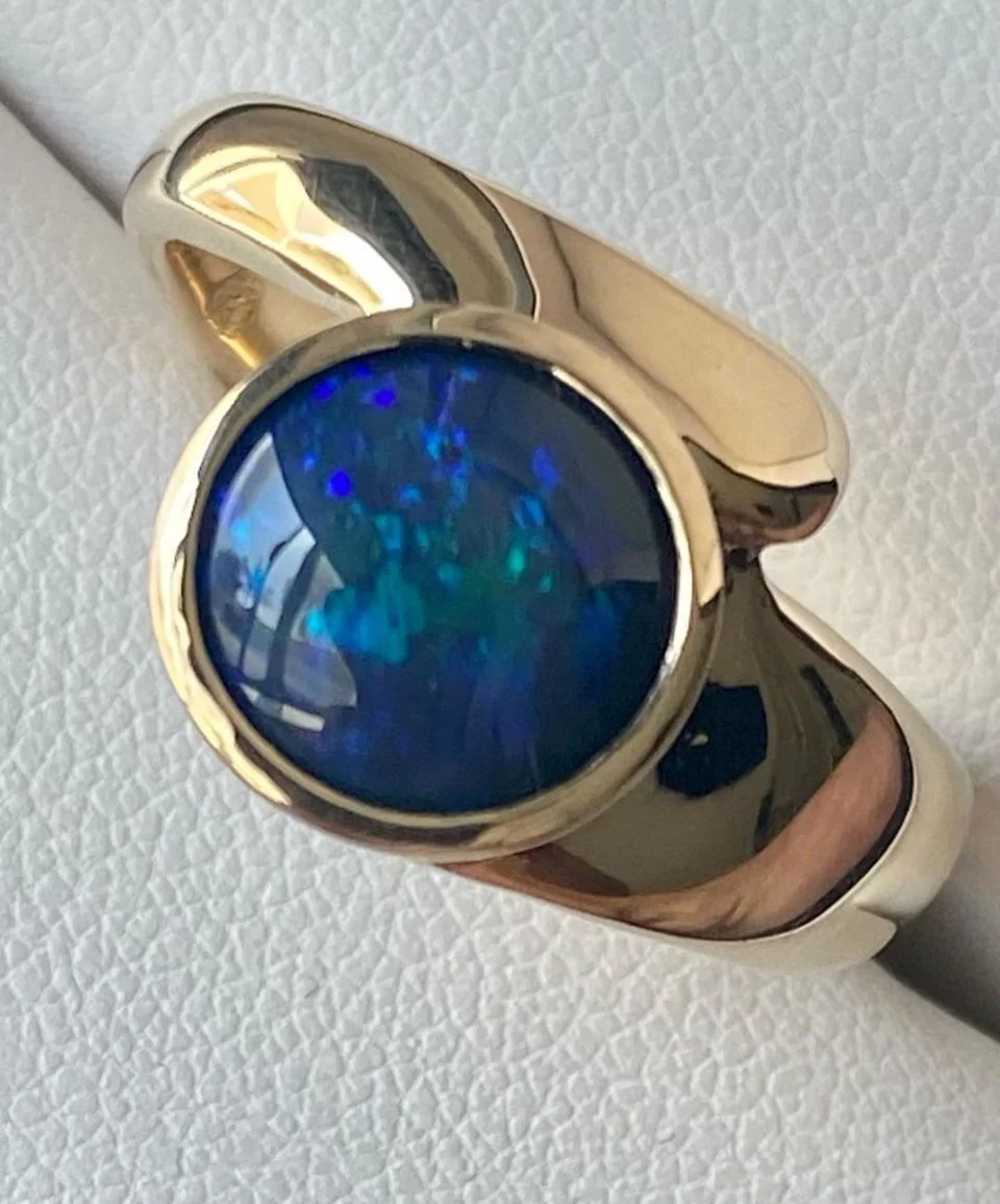 Gold ring with a round blue opal gemstone