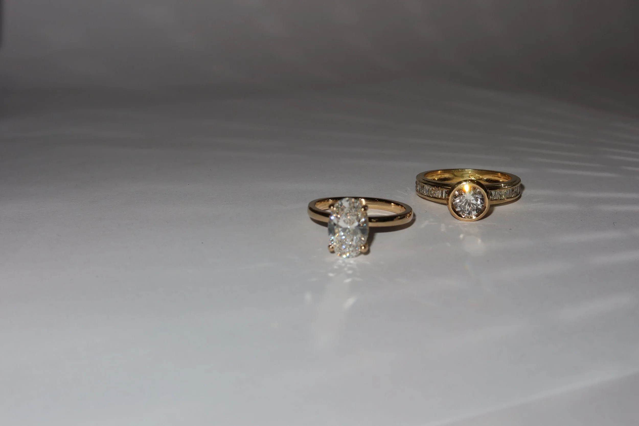 Two gold rings with diamonds on a white surface.