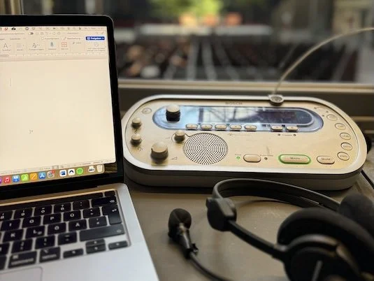Ein Laptop, eine Dolmetschkonsole und ein Headset in einer Dolmetschkabine.