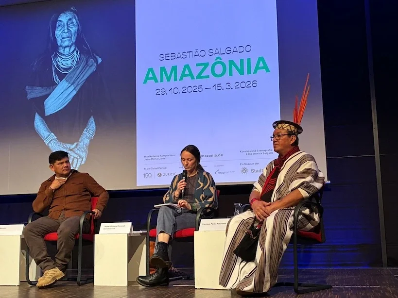 Podiumsdiskussion bei einer internationalen Veranstaltung mit Dolmetscherin auf der Bühne.