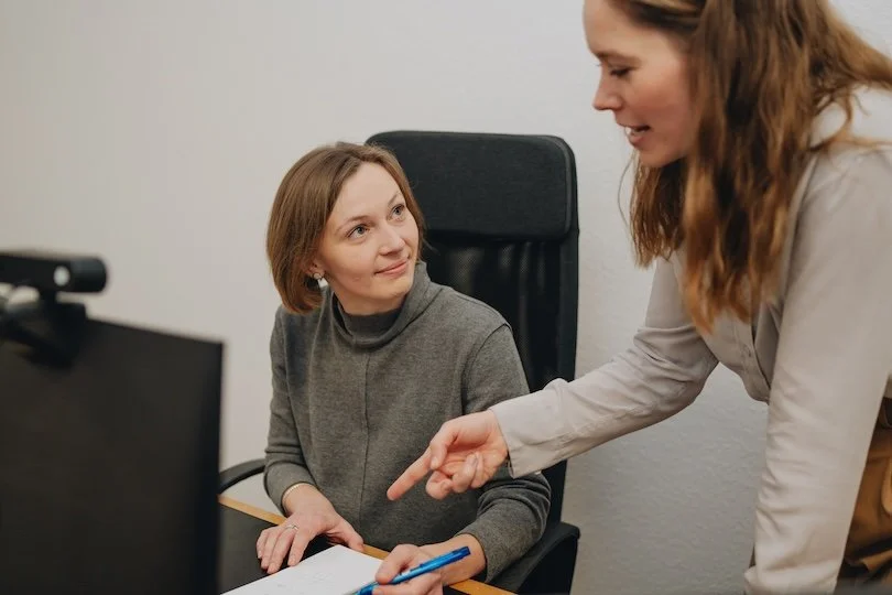 Zwei Dolmetscherinnen vor einem Computer und Notizblock.