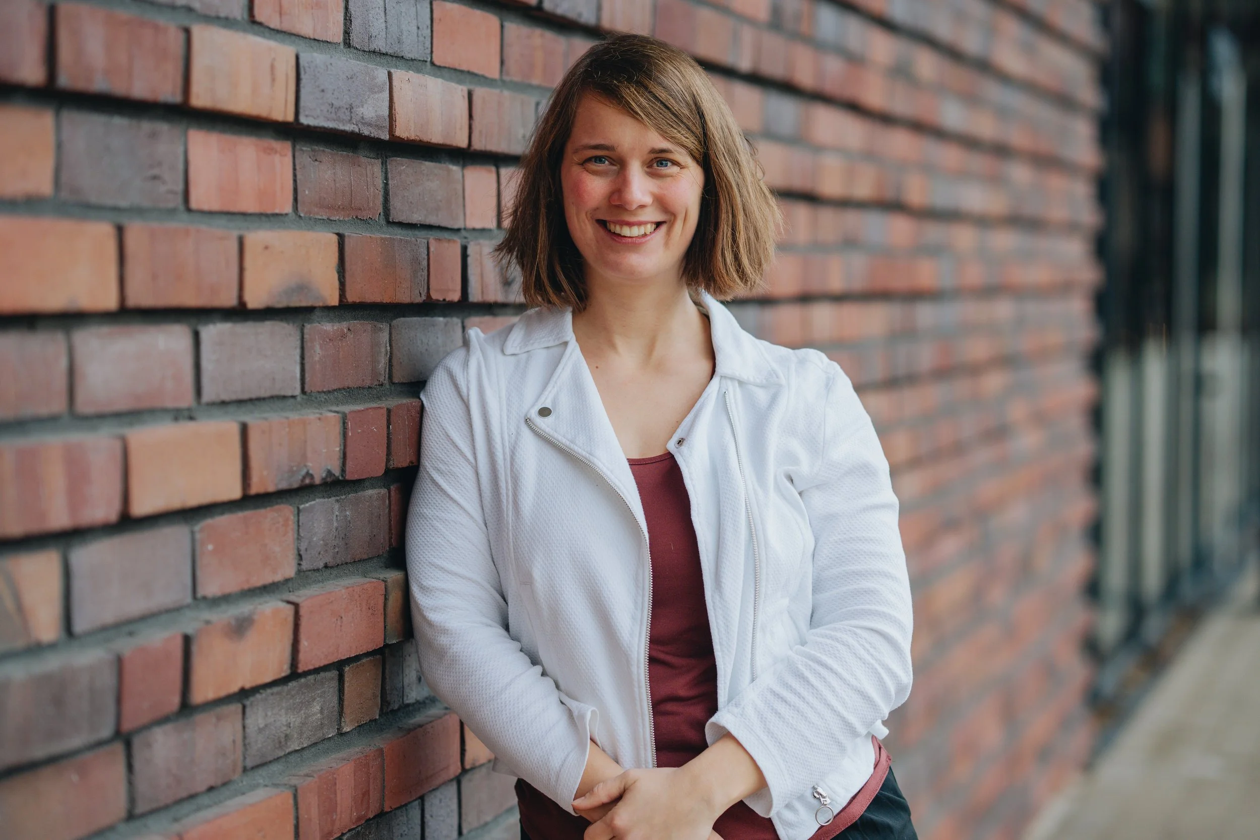 Eine Portraitaufnahme von Dolmetscherin Pia Duve vor einer Backsteinwand.