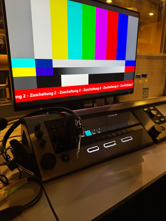 Eine Dolmetschkonsole vor einem Bildschirm mit dem Text: Zuschaltung 2.