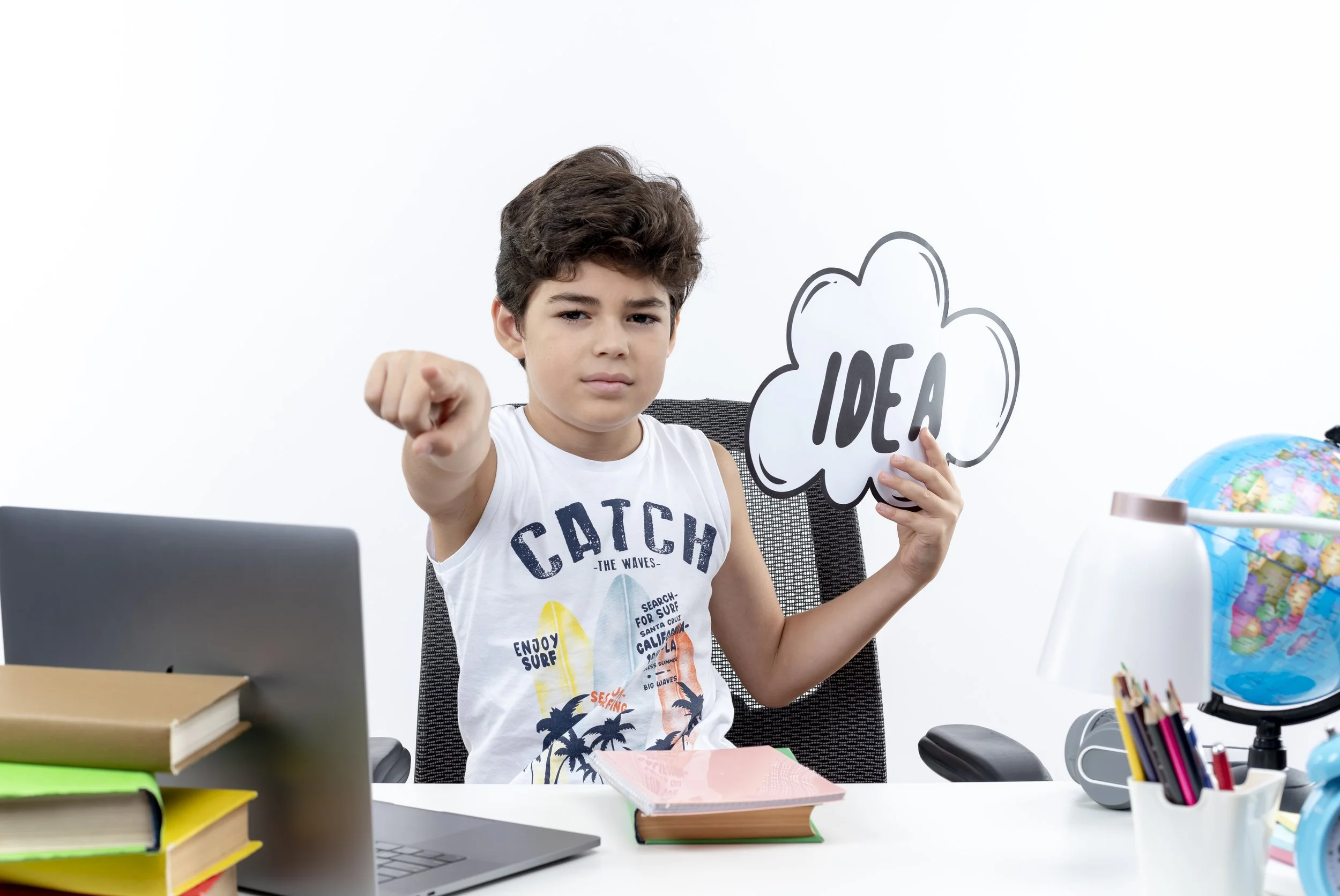 confident-little-schoolboy-sitting-desk-with-school-tools-holding-idea-bubble-showing-you-gesture-isolated-white-background.jpg