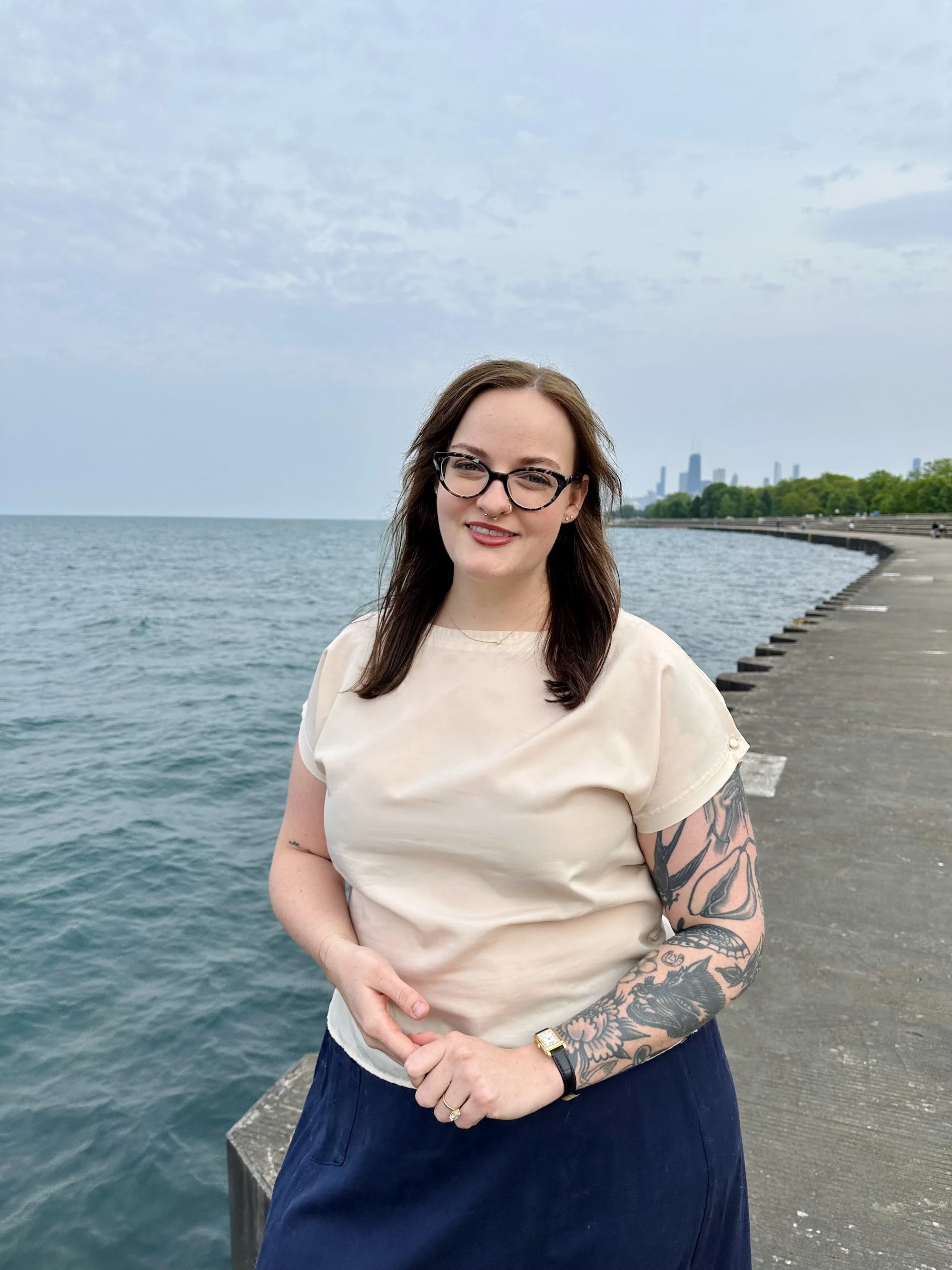 Marlee Gebhard, LCSW standing by a the Chicago lakefront with the skyline in the background, wearing a beige top and dark skirt.
