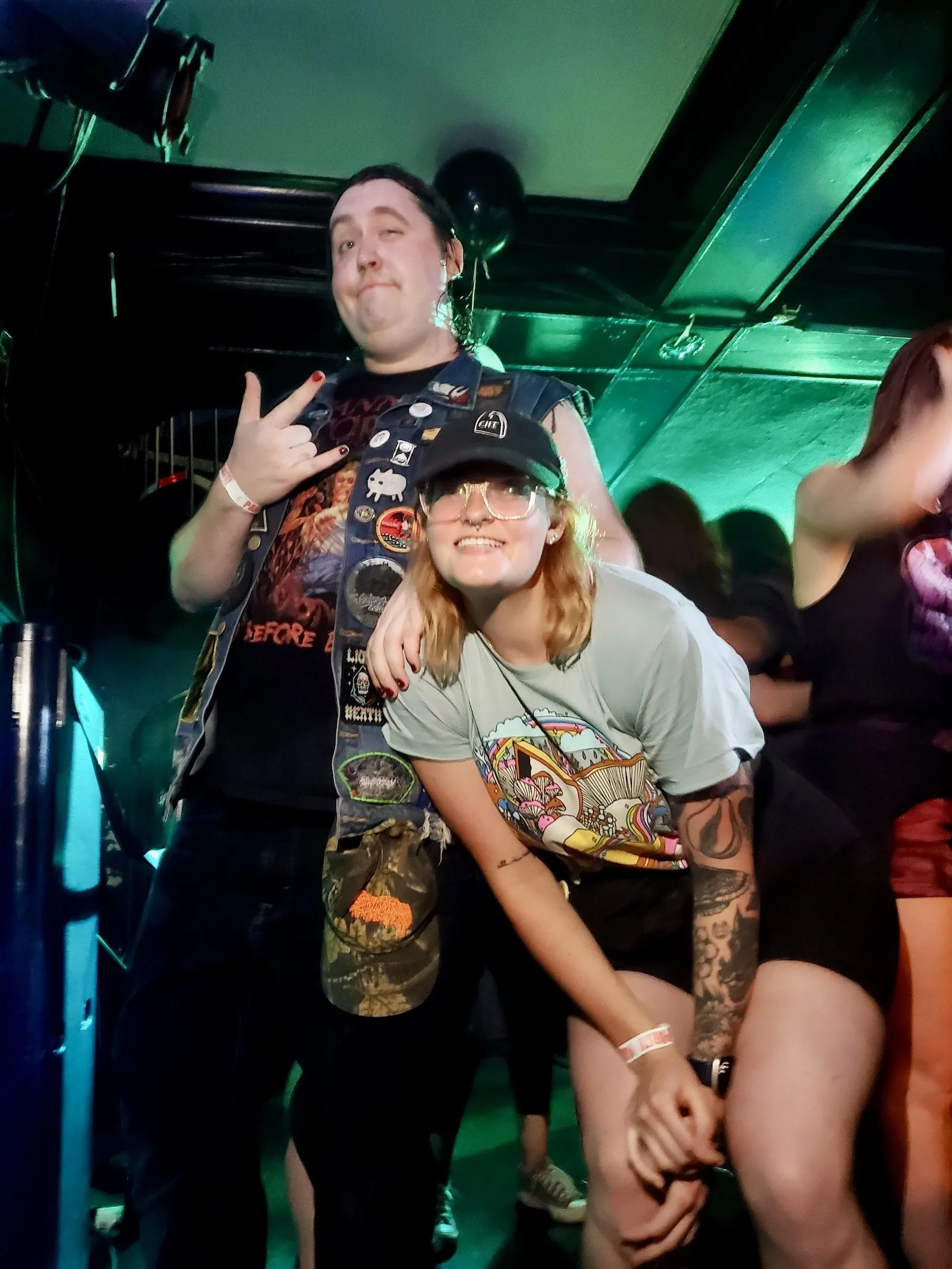 Marlee, and a friend, at an emo night concert, smiling and enjoying the event. Marlee specializes in LGBTQ therapy, Autism and neurodivergent affirming therapy, anxiety, self esteem, and sex therapy.