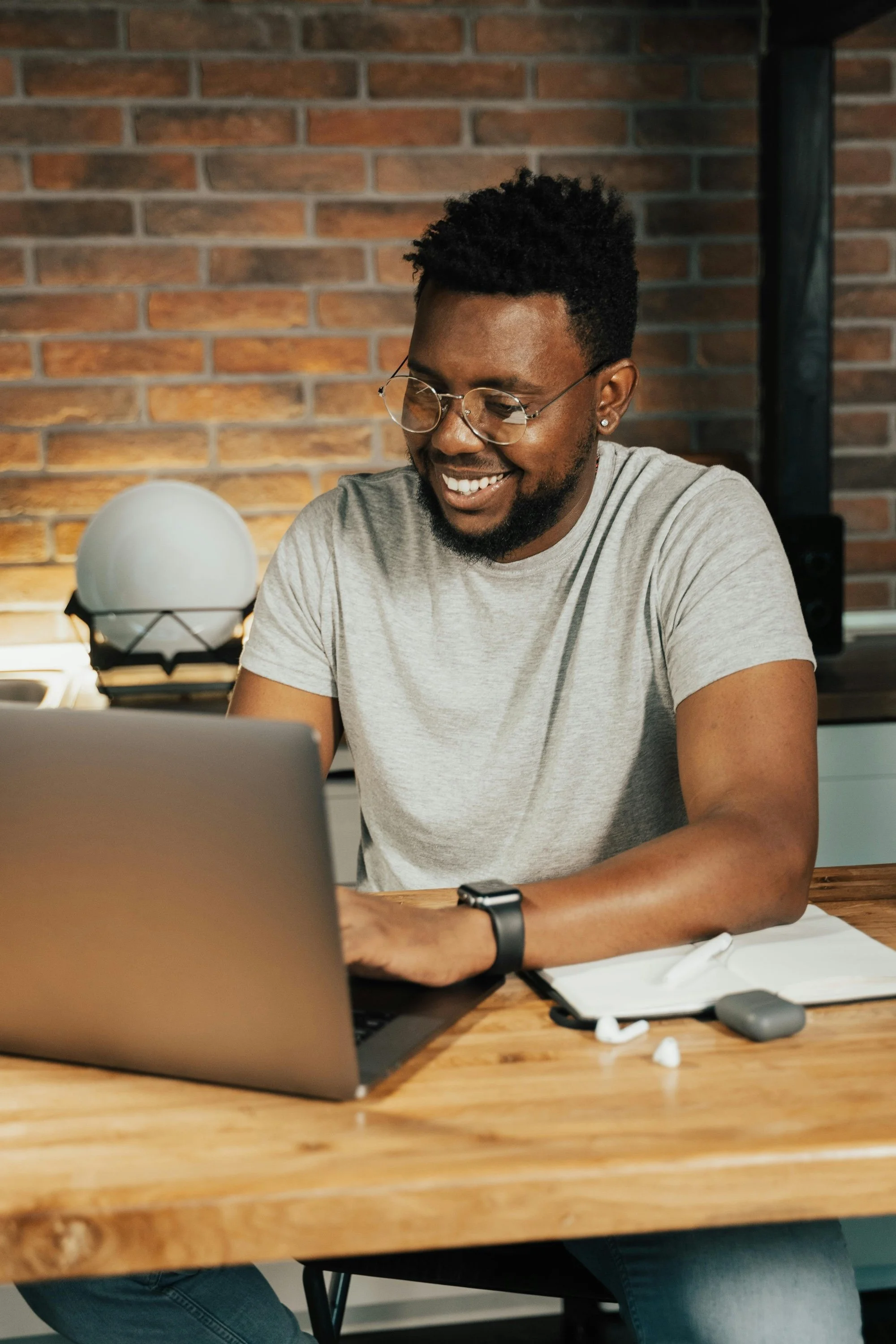 Black masc person with glasses and a gray shirt on their laptop, scheduling a session with Marlee, autism-affirming sex therapist, in Colorado