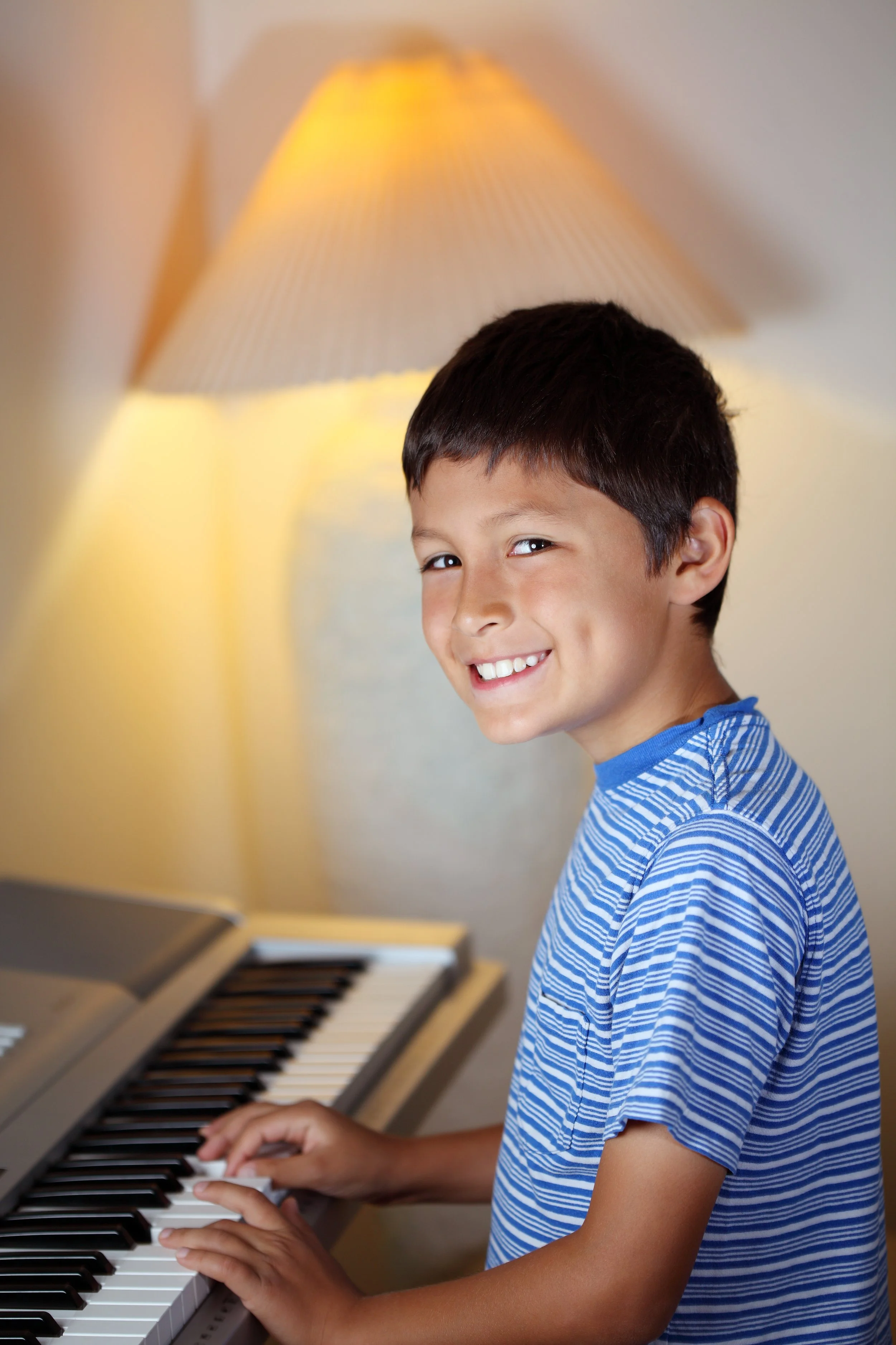 boy playing piano striped blue shirt.jpeg
