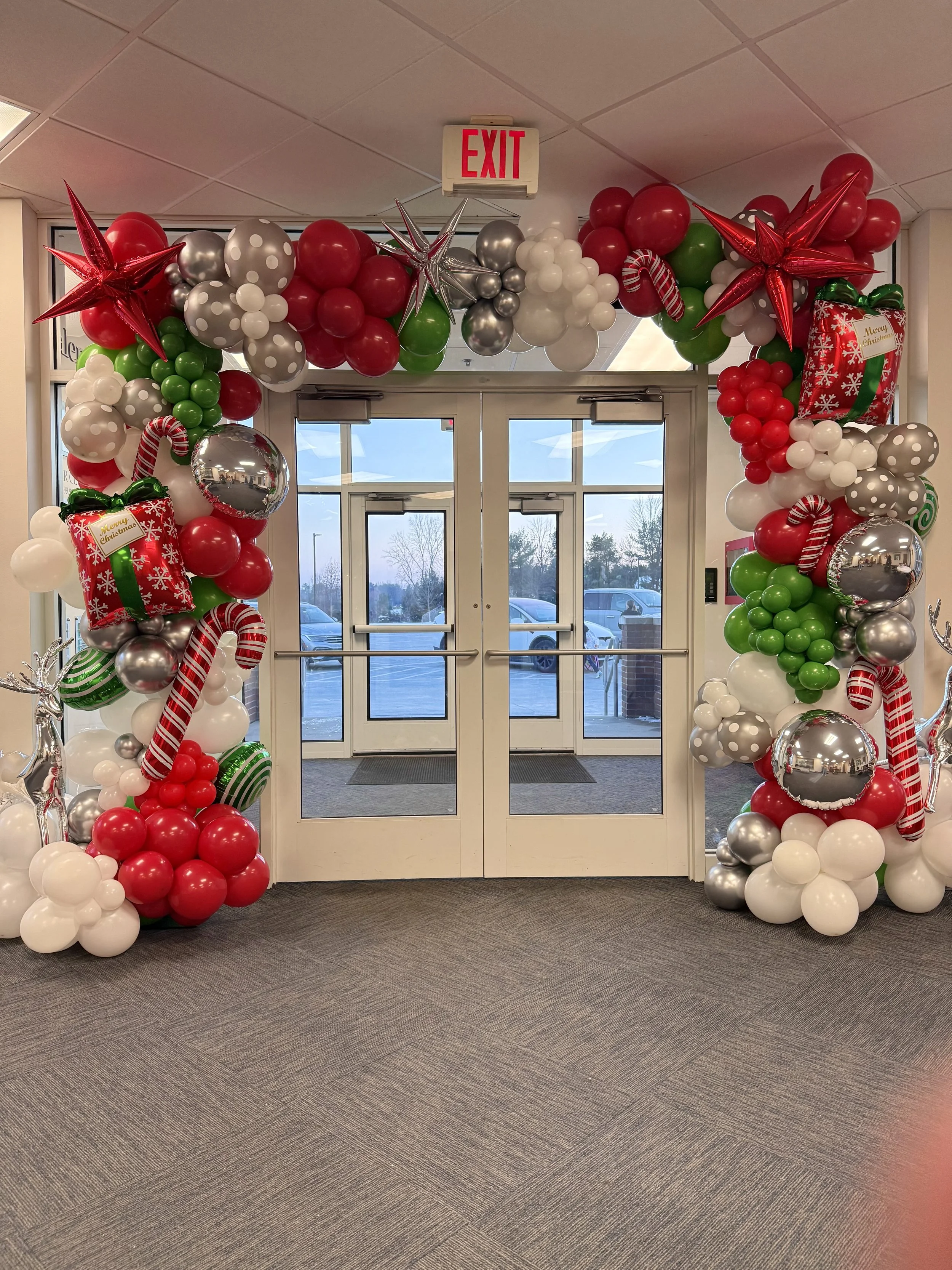 red, white, and silver balloons around a two glass doors