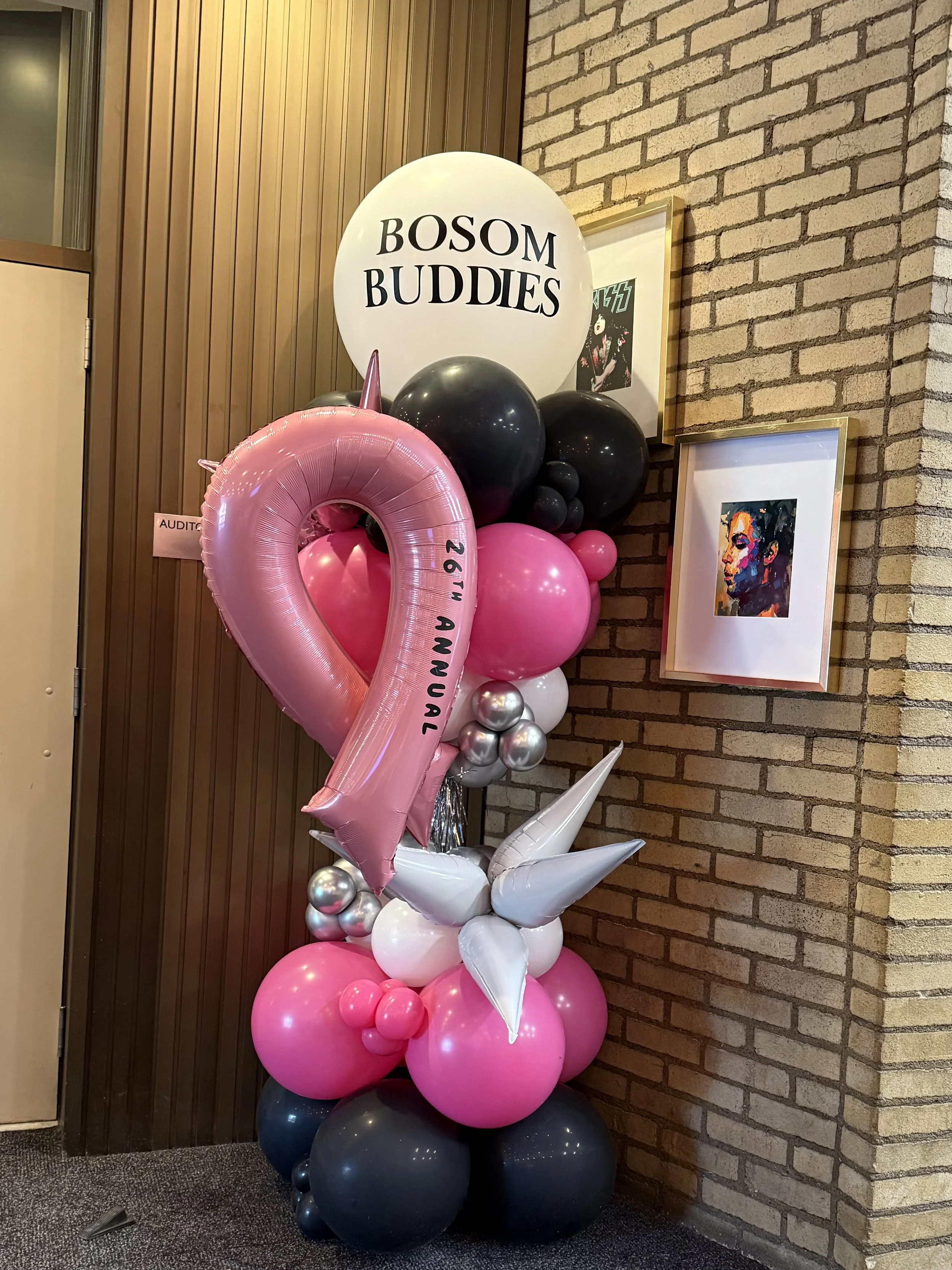 Balloon column with a pink ribbon balloon and a white balloon that says Bosom Buddies