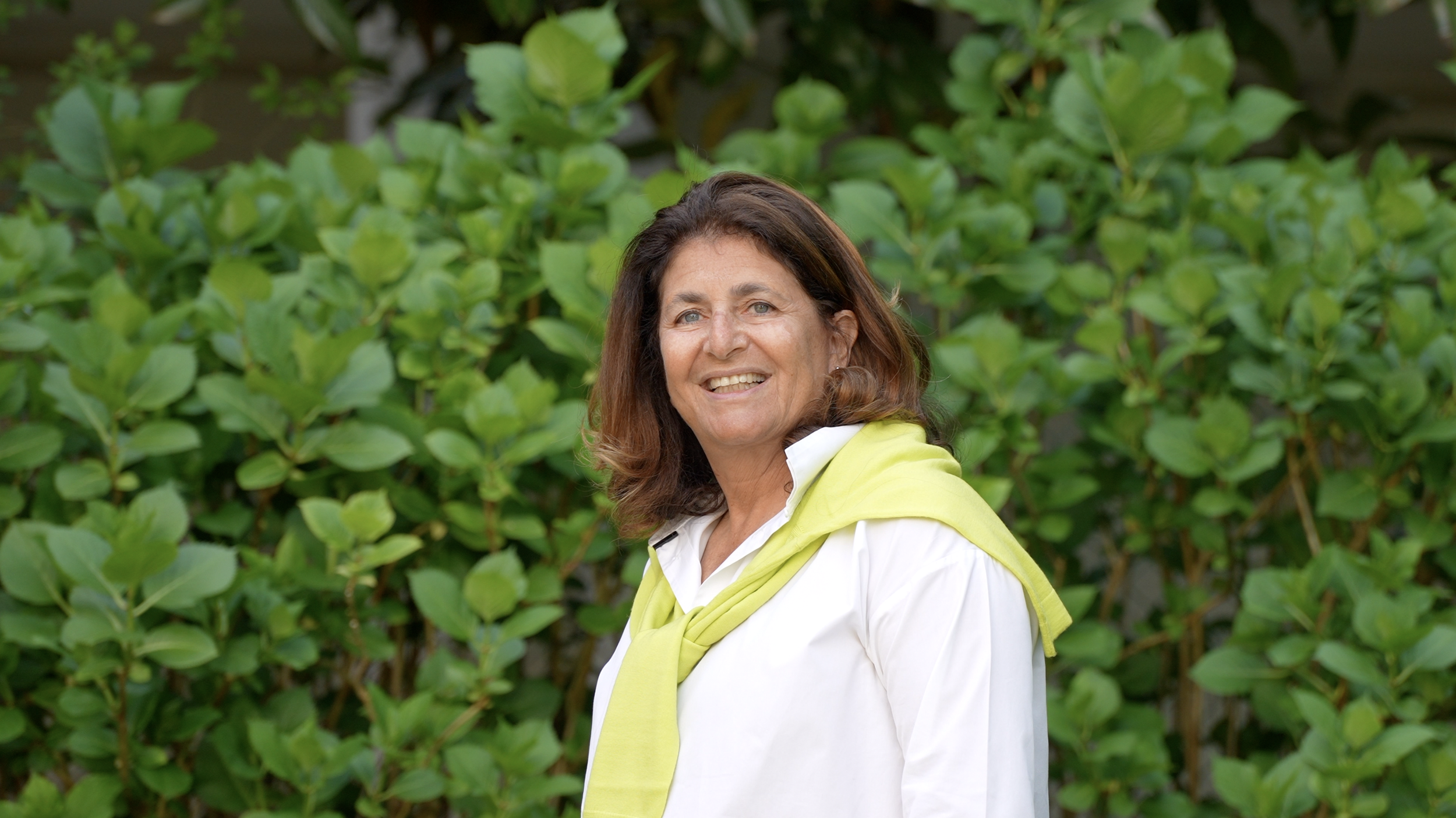 Directrice souriante de l’École Eden, Magali, devant un cadre verdoyant, reflétant accueil, bienveillance et leadership éducatif.
