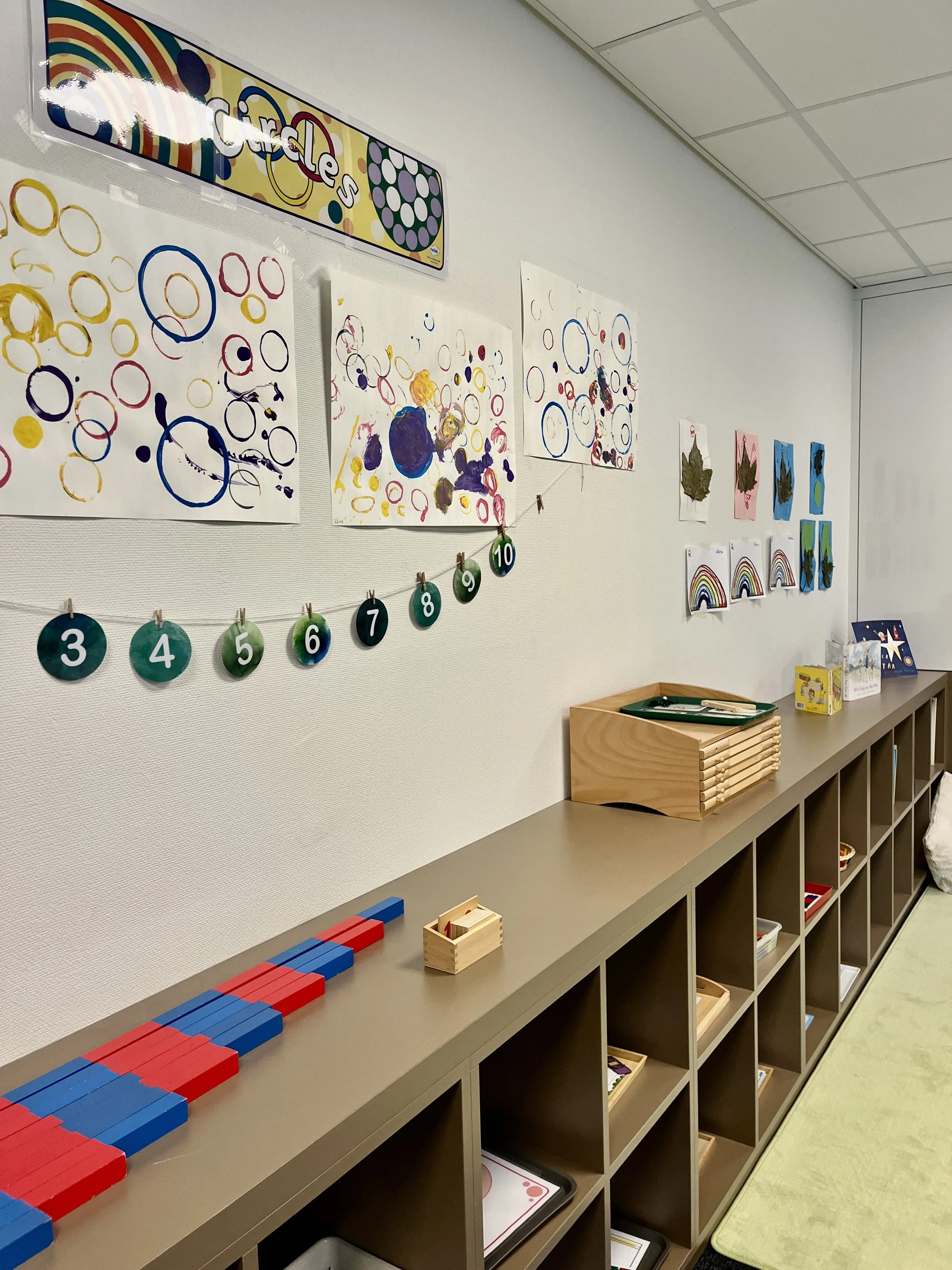 Espace de classe à l’École Eden avec œuvres d’art d’élèves, supports pédagogiques, étagères en bois et matériel éducatif favorisant autonomie et apprentissage.