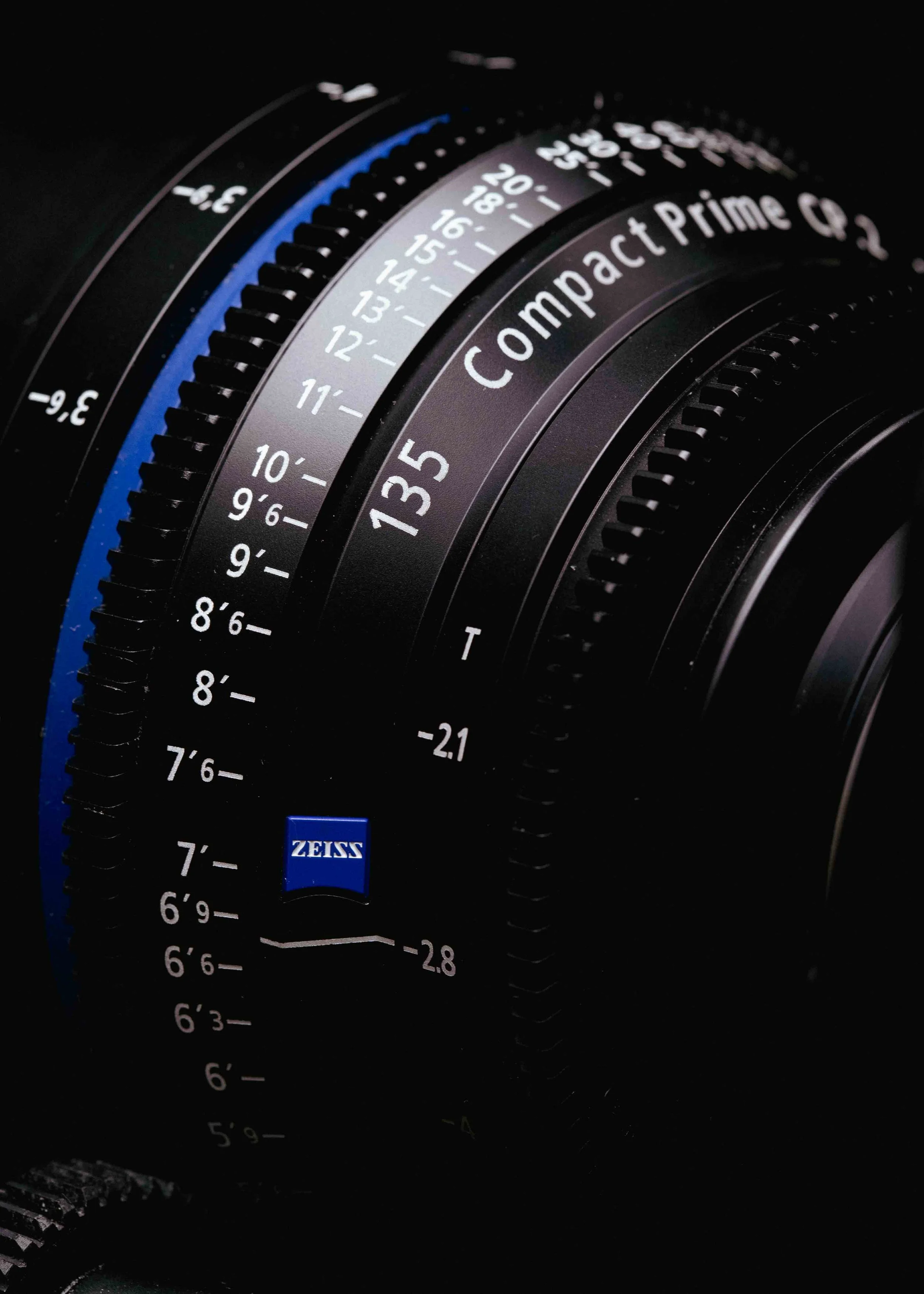 Close-up of a camera lens with focus distance markings and Zeiss branding.