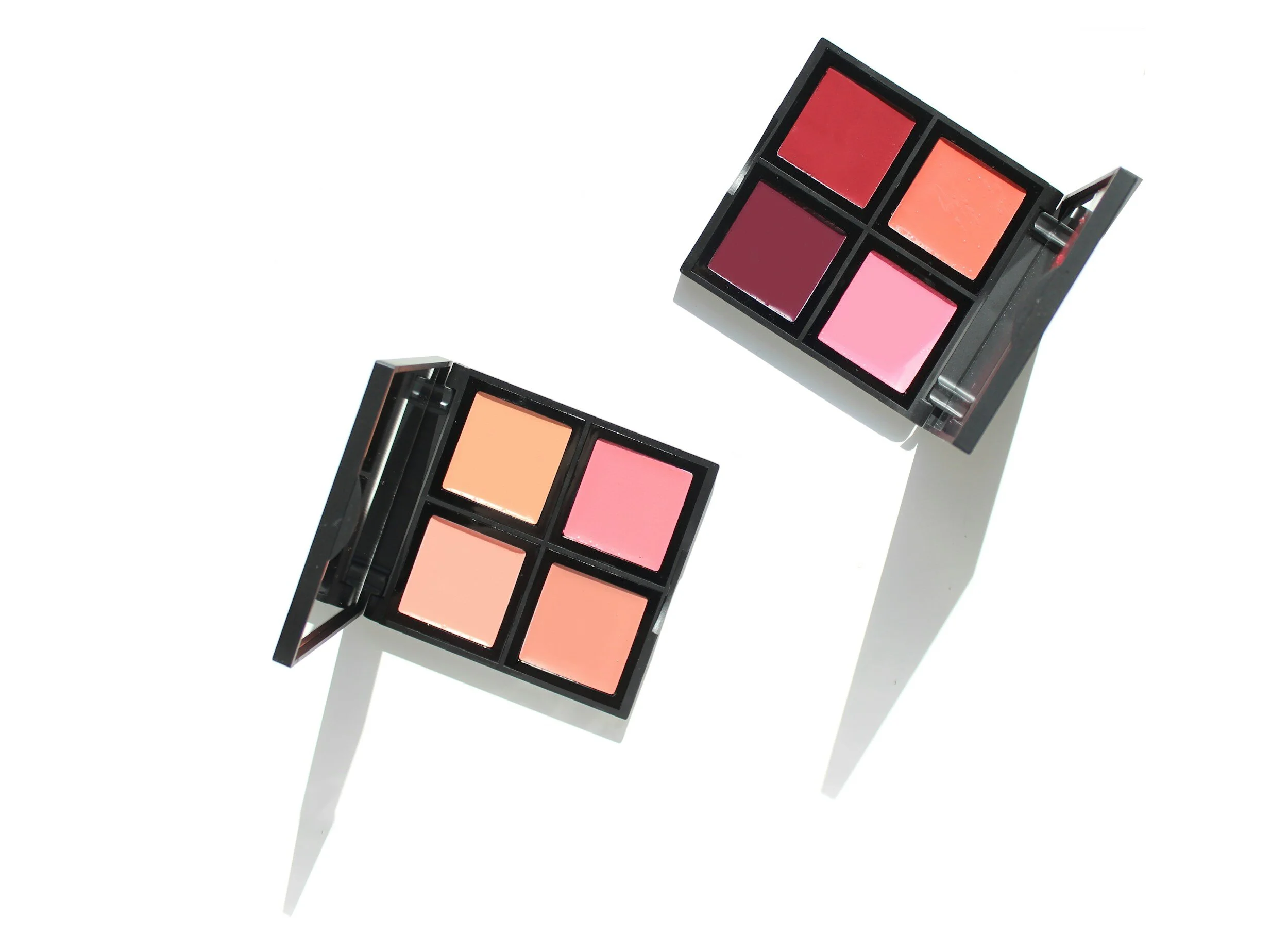 Two black rectangular makeup palettes with five colorful blush or eyeshadow shades each, positioned on a white background with shadows.