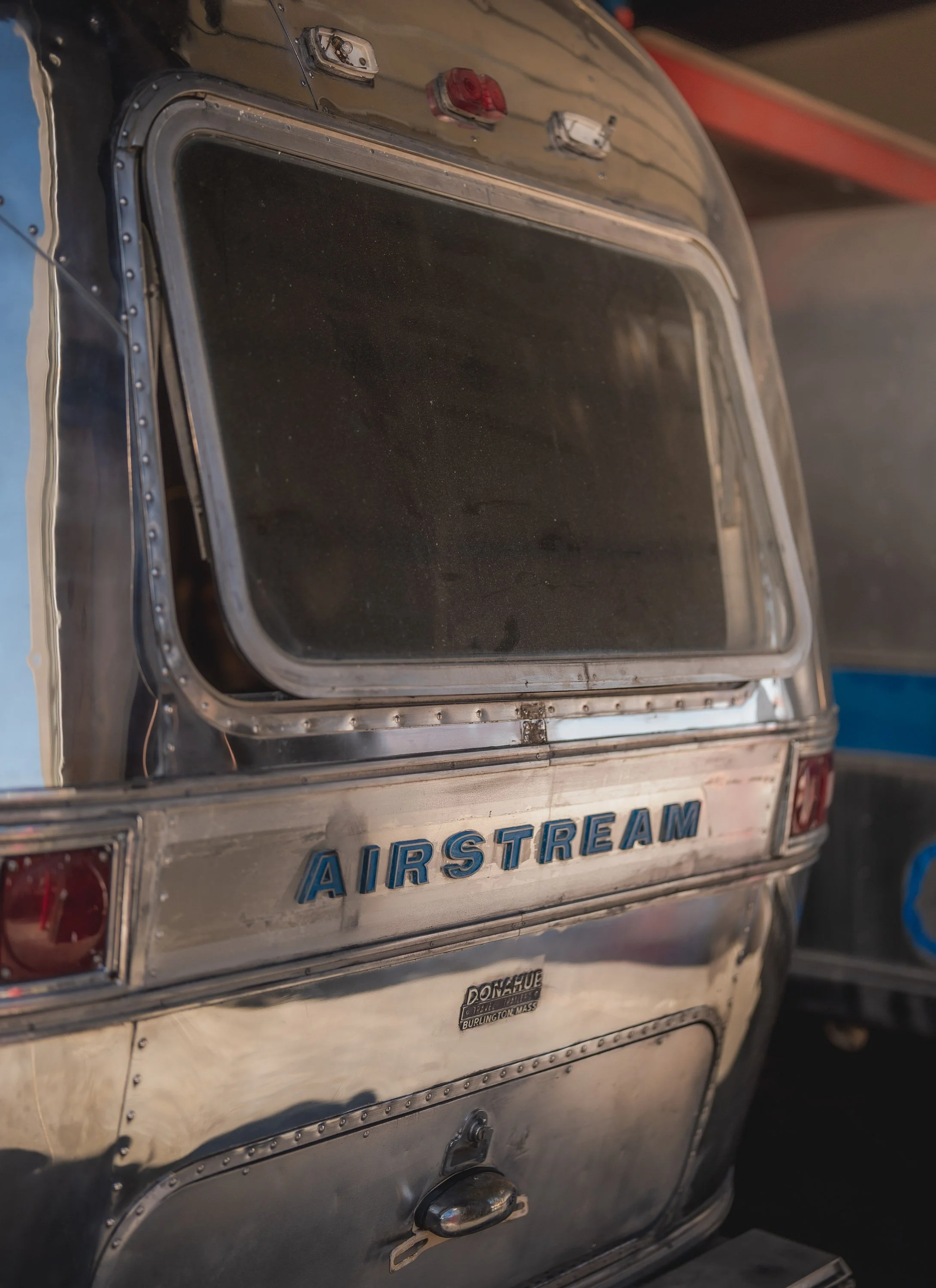 Close-up of a vintage Airstream trailer with a shiny metallic exterior and a large window at the rear.