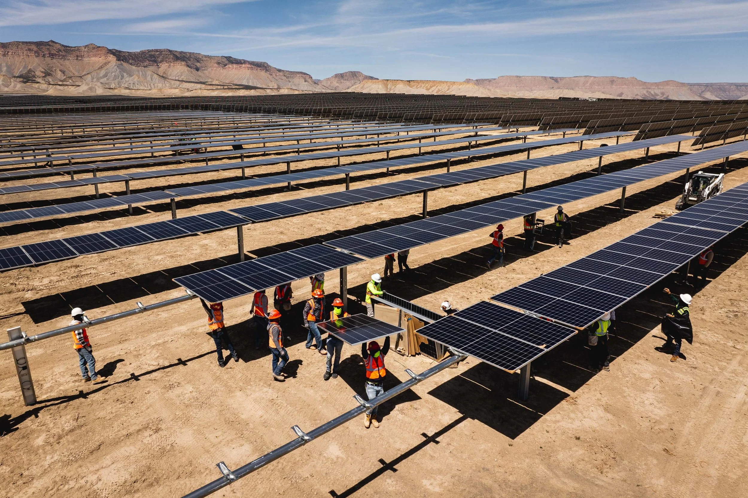 Construction workers installing solar panels in a desert landscape.