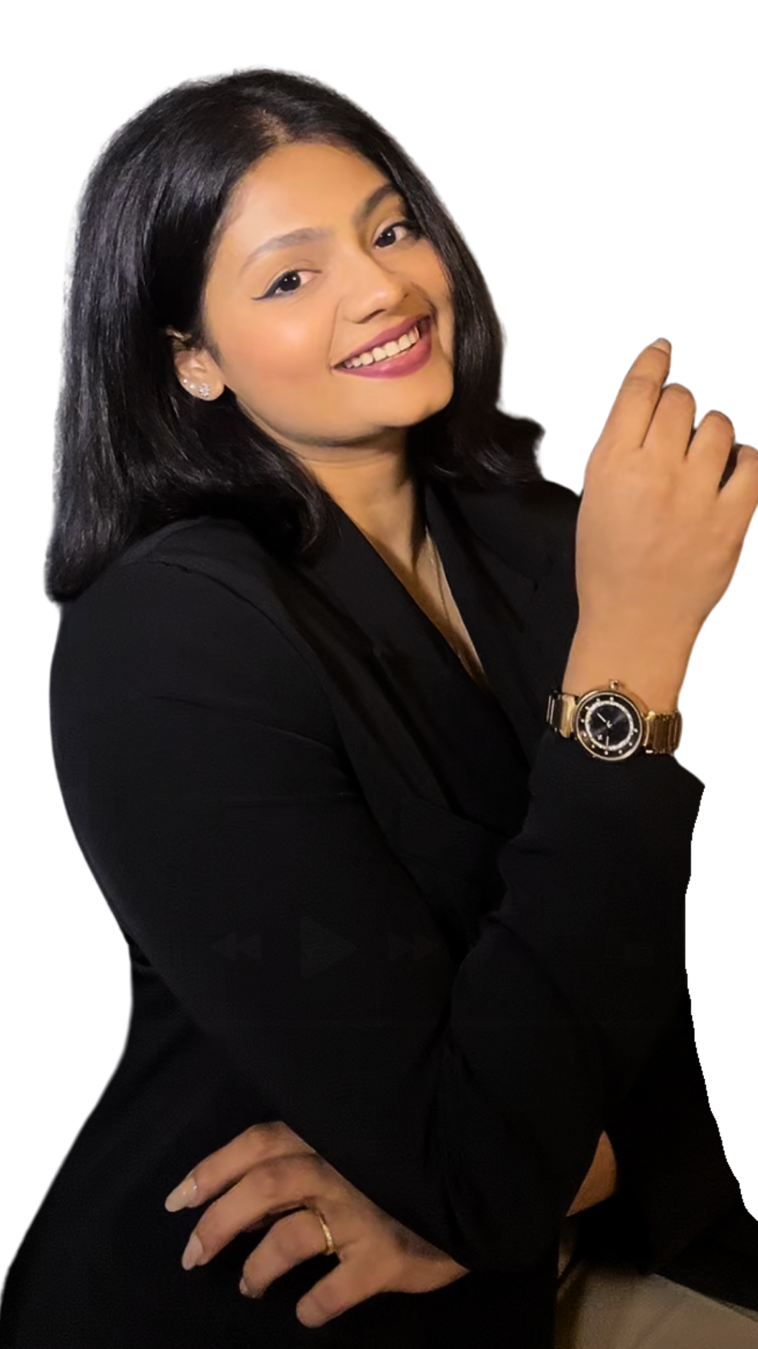 A woman with shoulder-length black hair, wearing a black blazer, gold watch, and earrings, smiling with one hand on her hip and the other raised, against a plain black background.