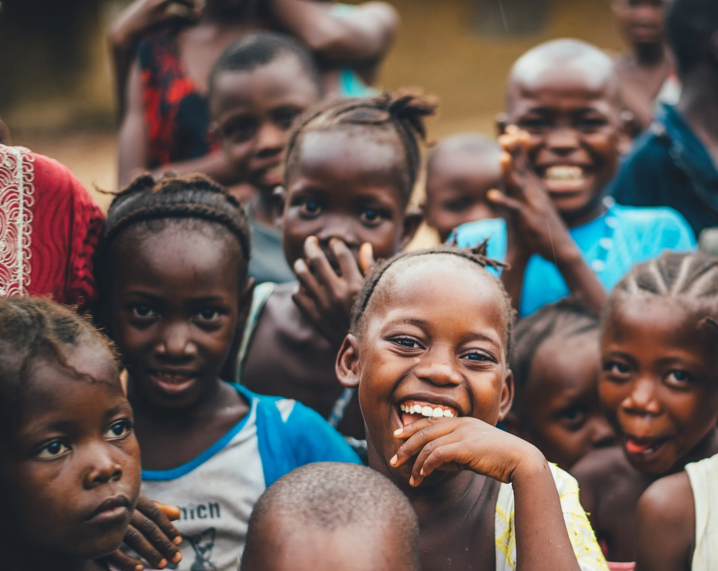 Group of smiling children outdoors, some looking at the camera.
