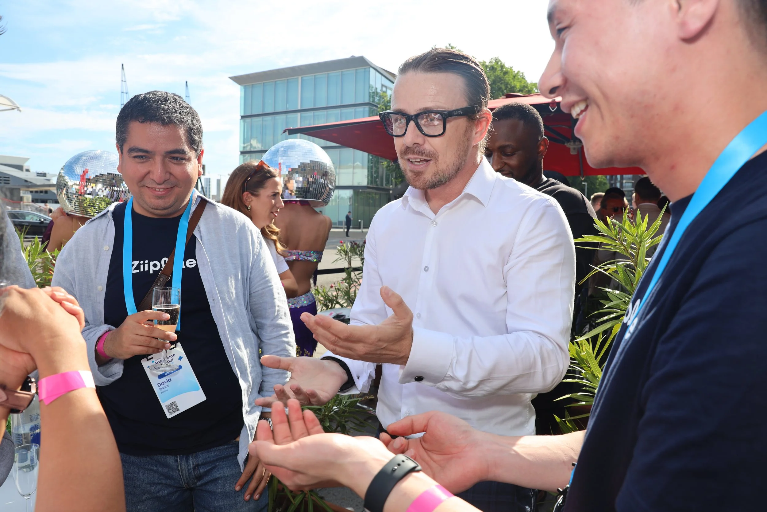 Just Saul performing close-up magic with a bracelet trick for guests at an outdoor corporate event