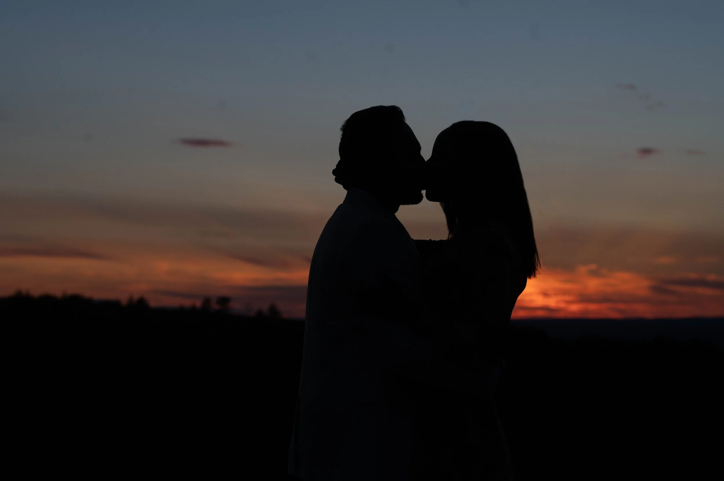 Silhouette of a couple kissing at sunset
